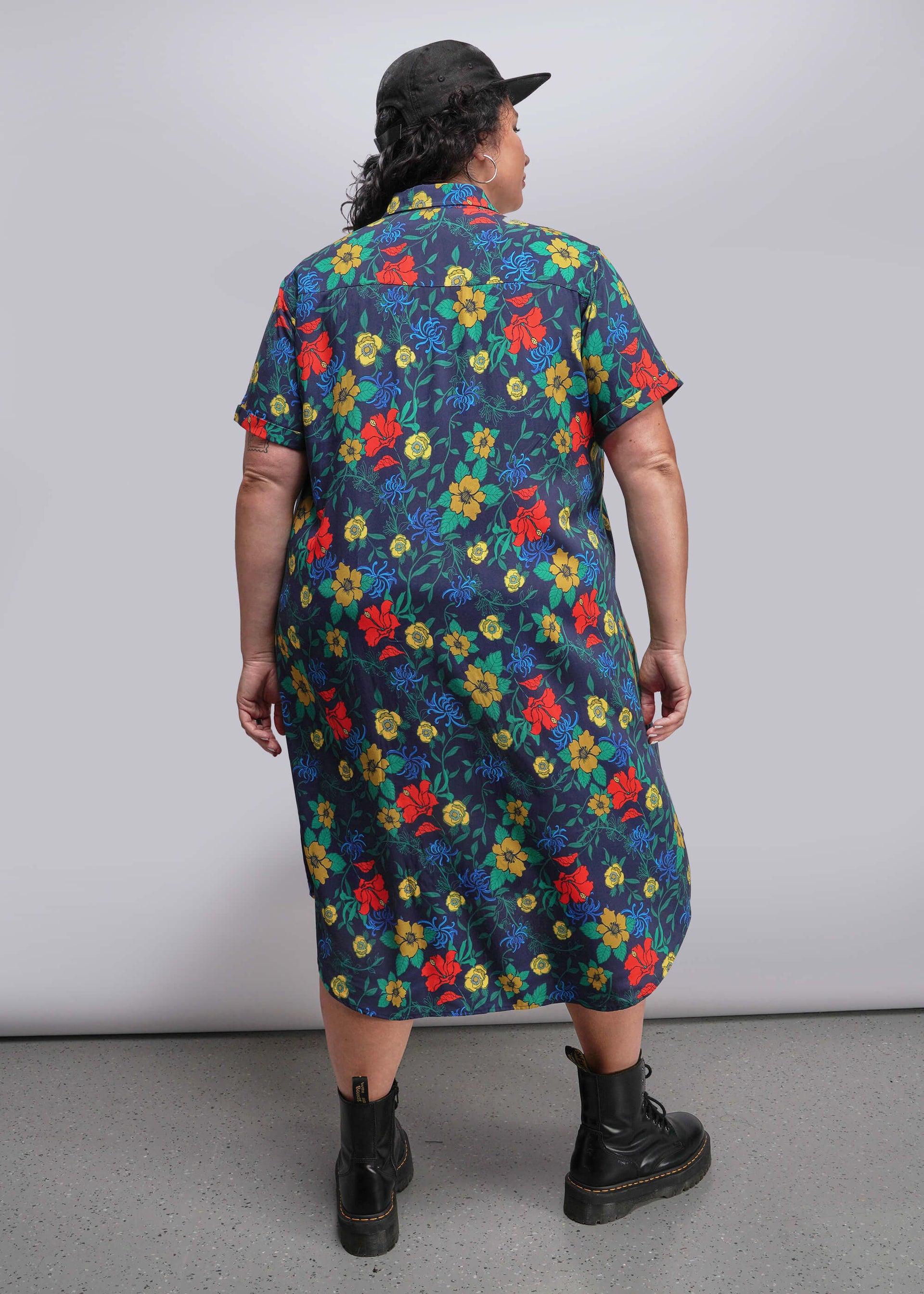 1X=Back view of person wearing a colorful floral dress with a plain background
