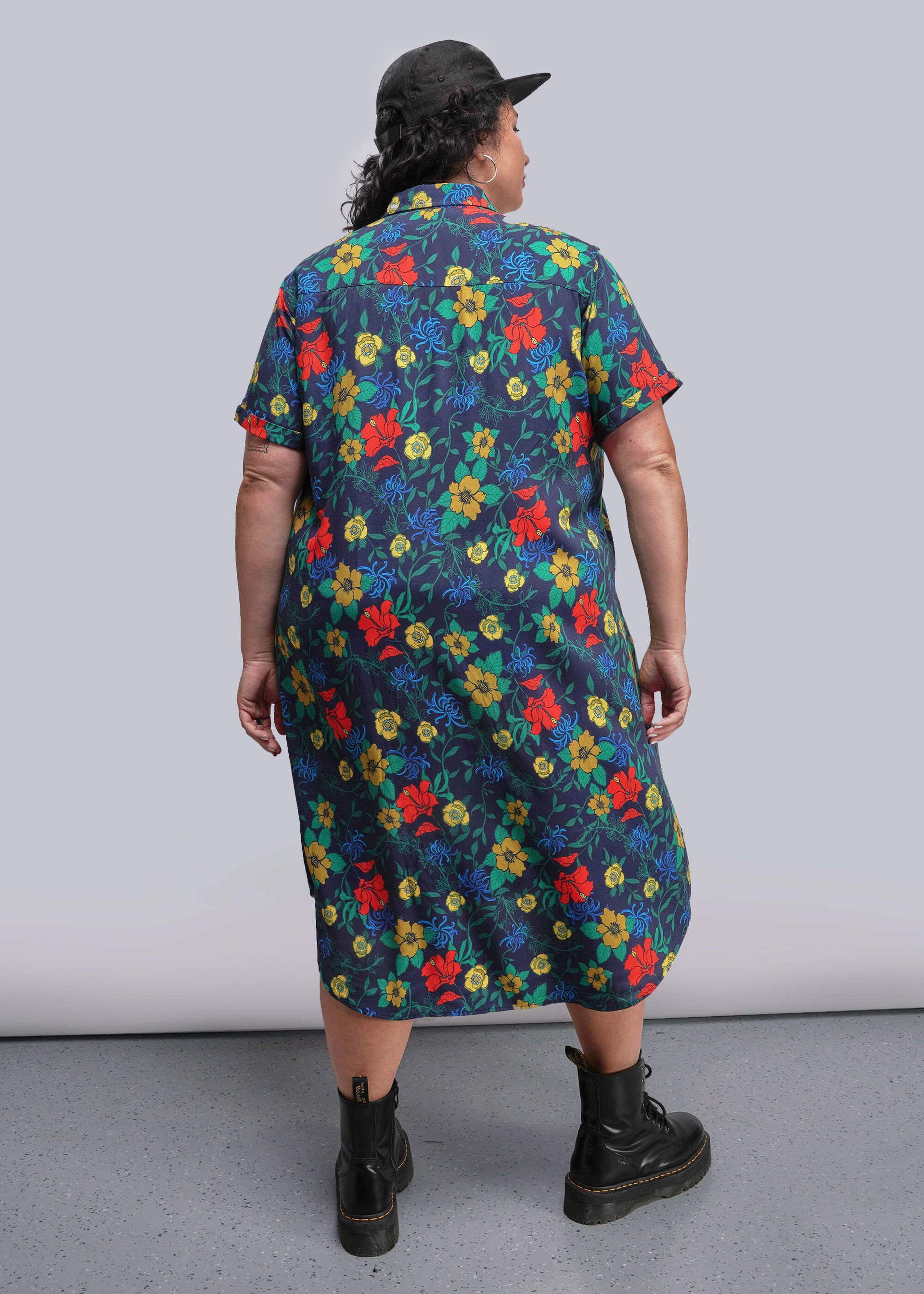1X=Back view of person wearing a colorful floral dress with a plain background