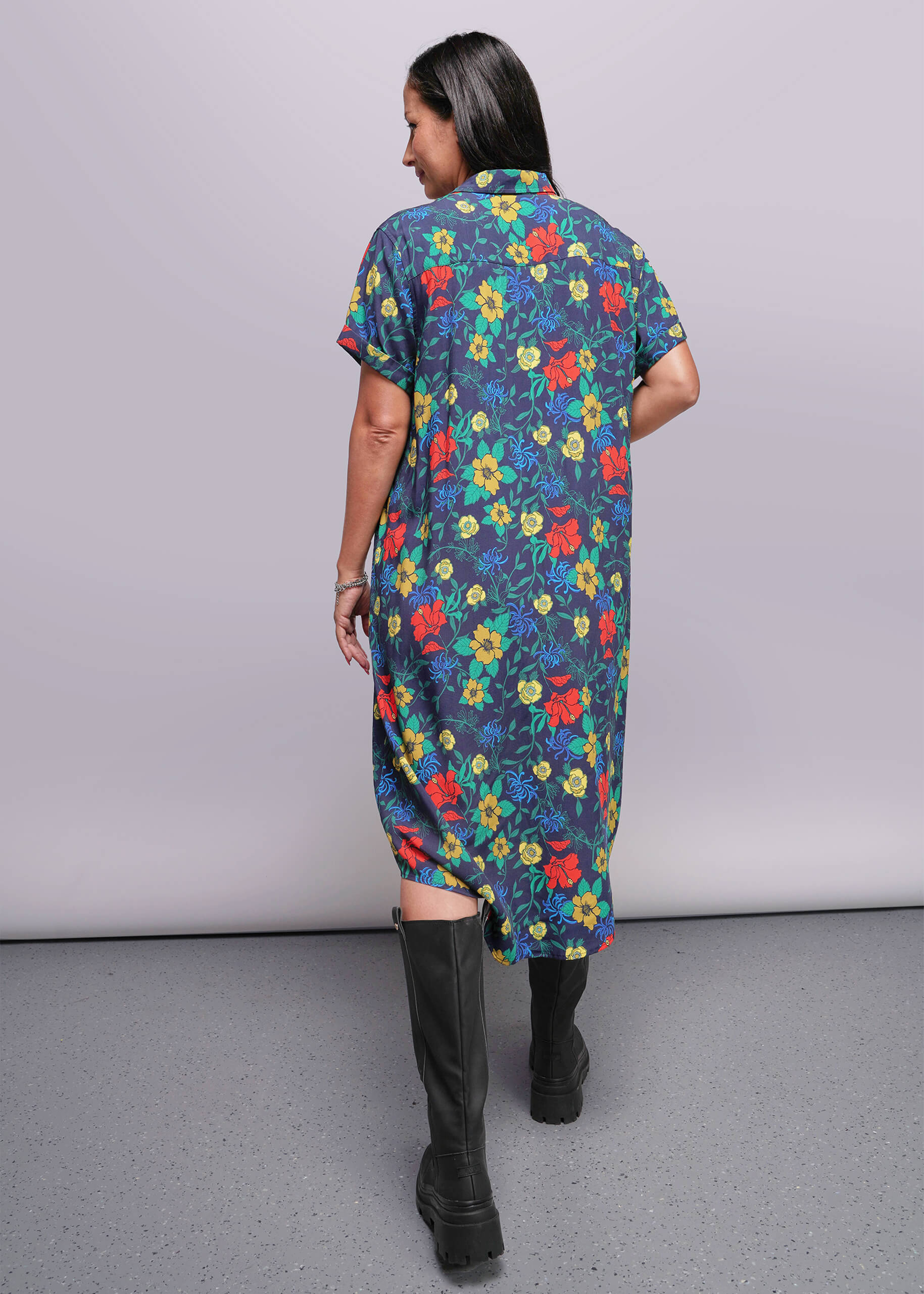 S=Woman wearing a colorful floral dress with a plain background