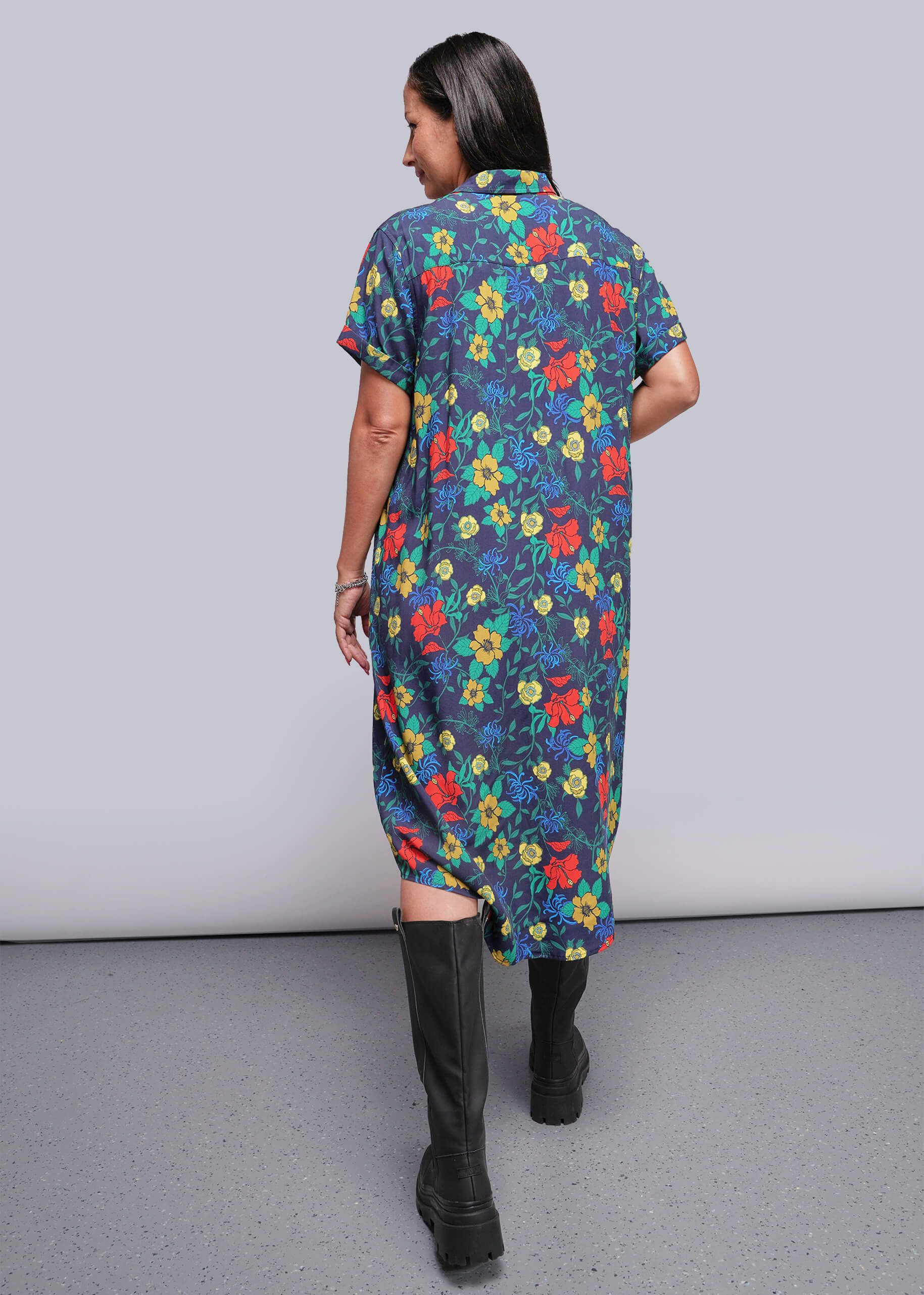 S=Woman wearing a colorful floral dress with a plain background