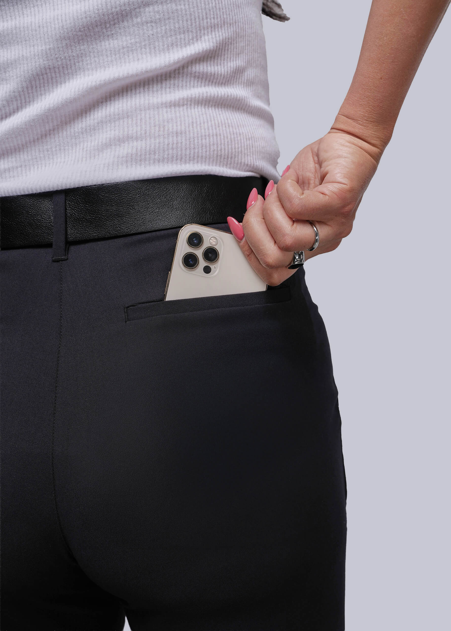 S=Person wearing black pants with a phone in the pocket against a plain background