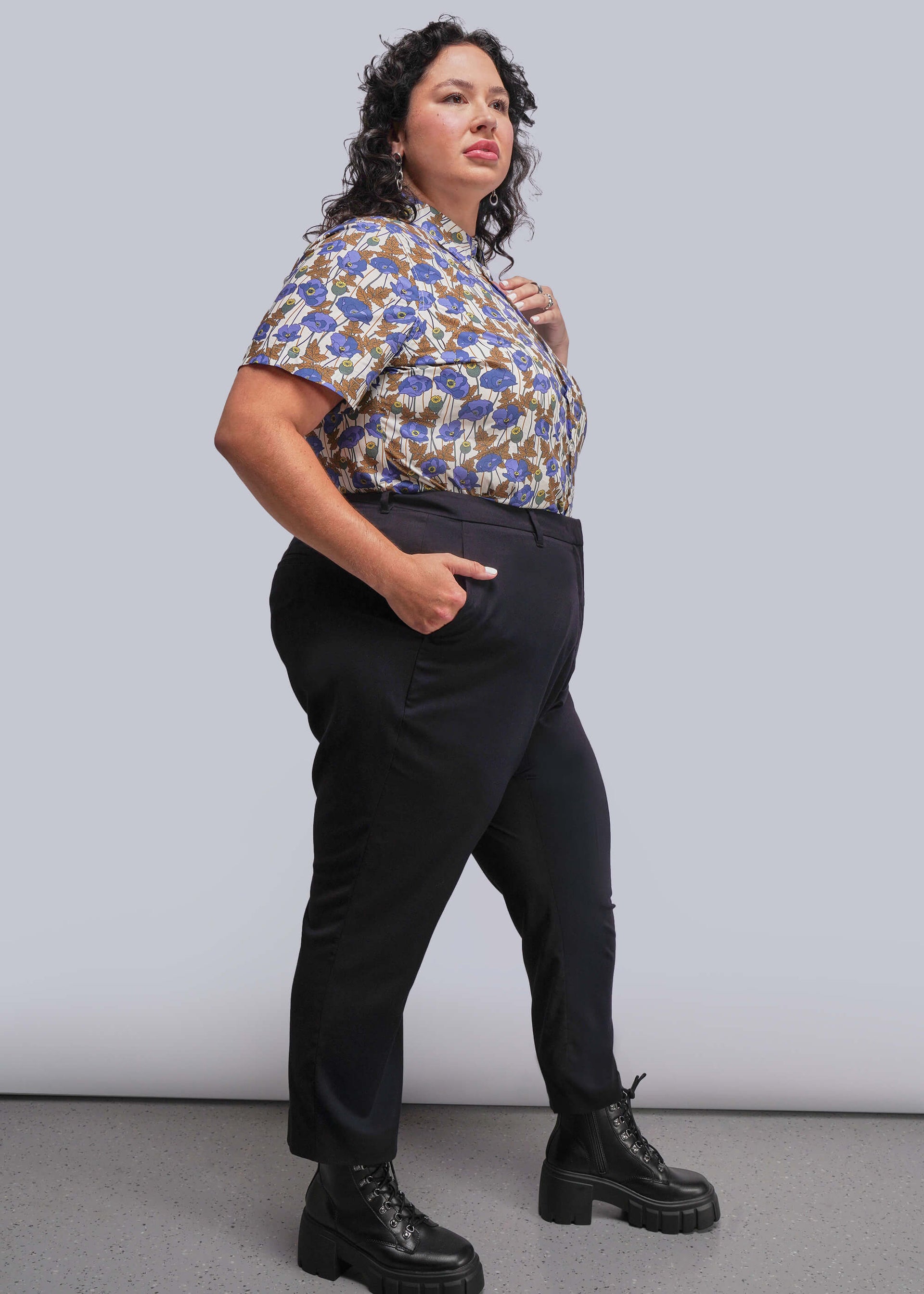 1x=Person wearing a patterned shirt and black pants against a plain background