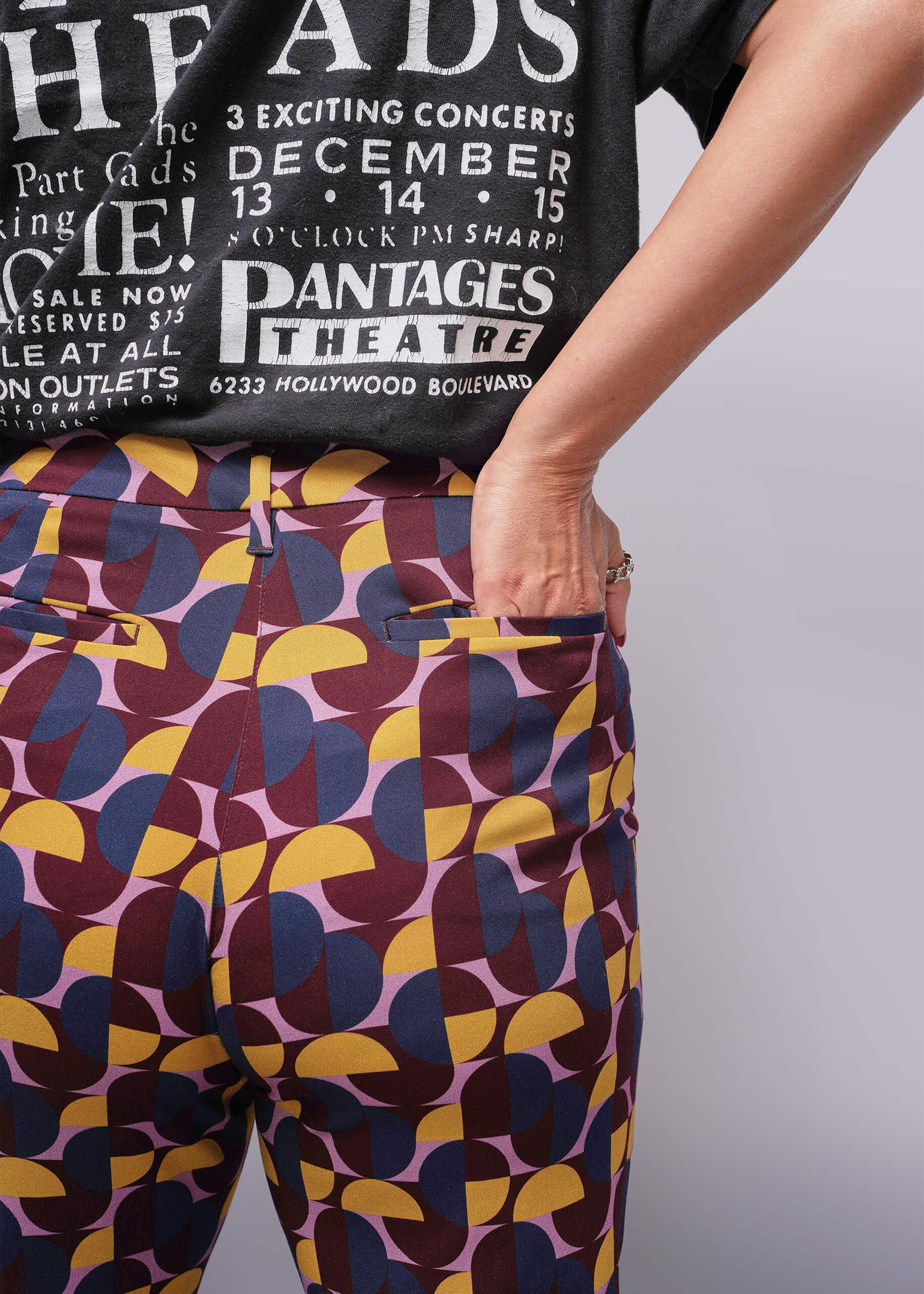 S=Person wearing a black t-shirt with white text and colorful patterned pants.