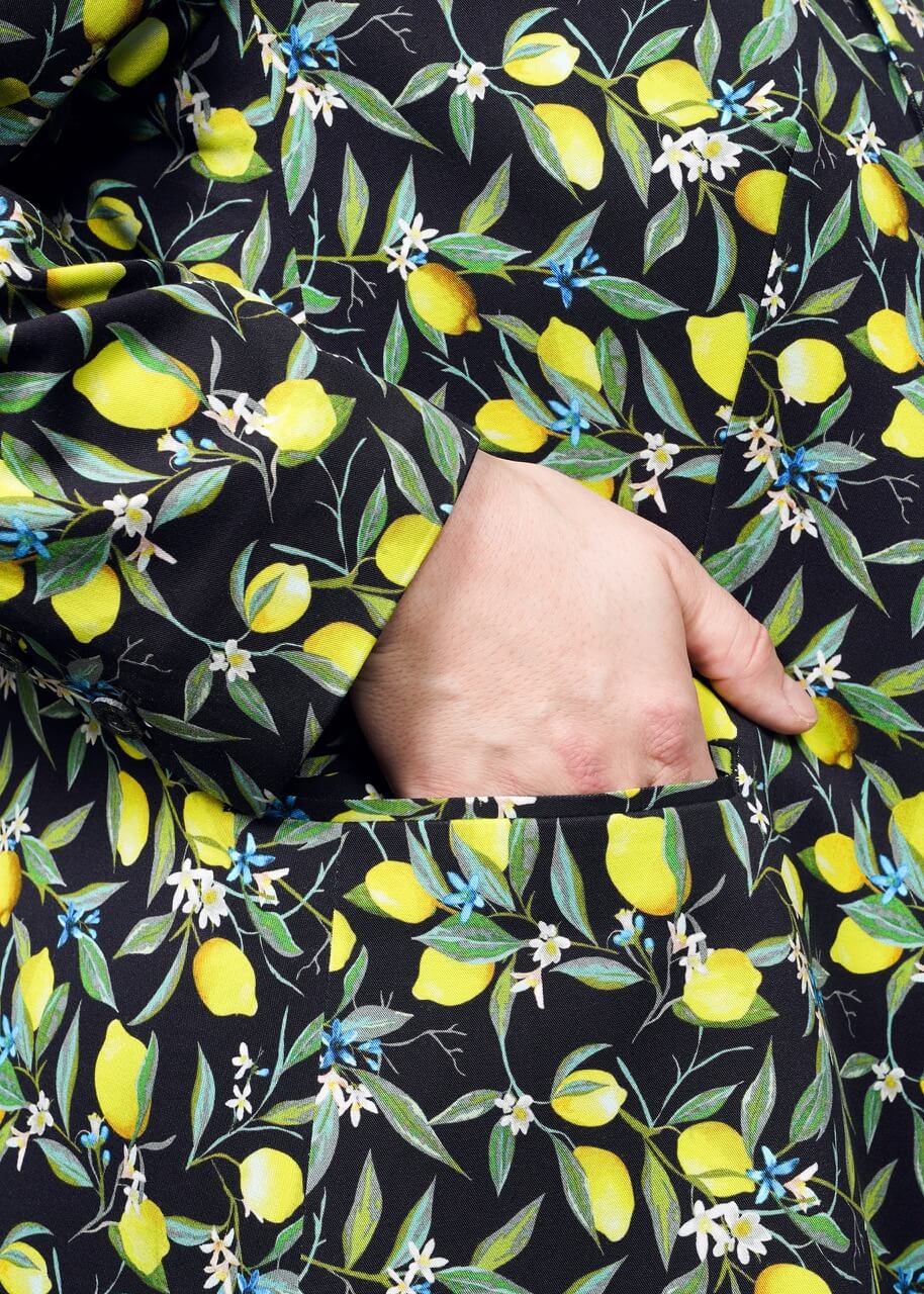 S=Close up of model hand in pocket on The Empower Tux Blazer in Citrus Black, which is a yellow and green print on black background featuring lemons and leaves.