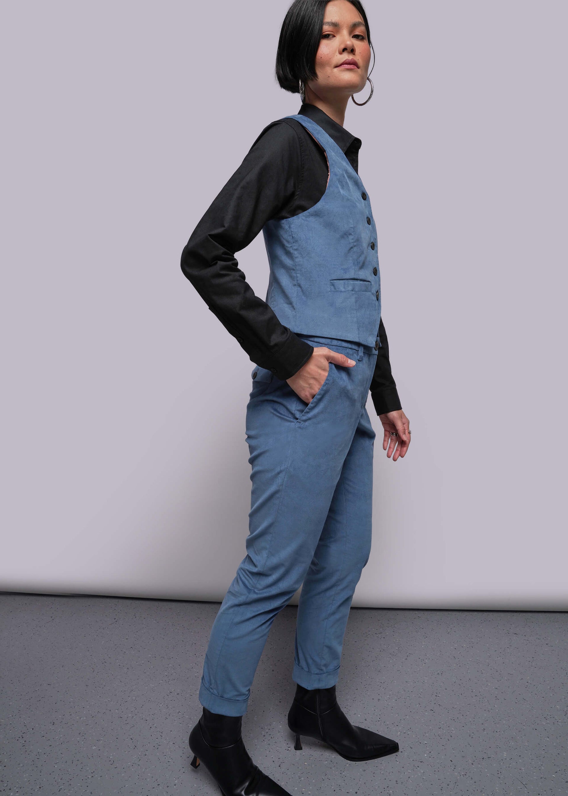 S=Person wearing a blue jumpsuit with a black shirt underneath on a plain background