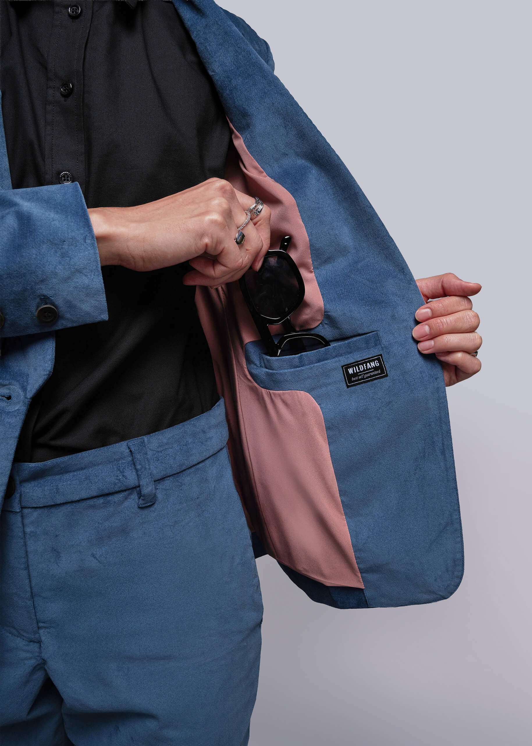 S=Person wearing a blue jacket with a pink inner lining, holding a black bottle.