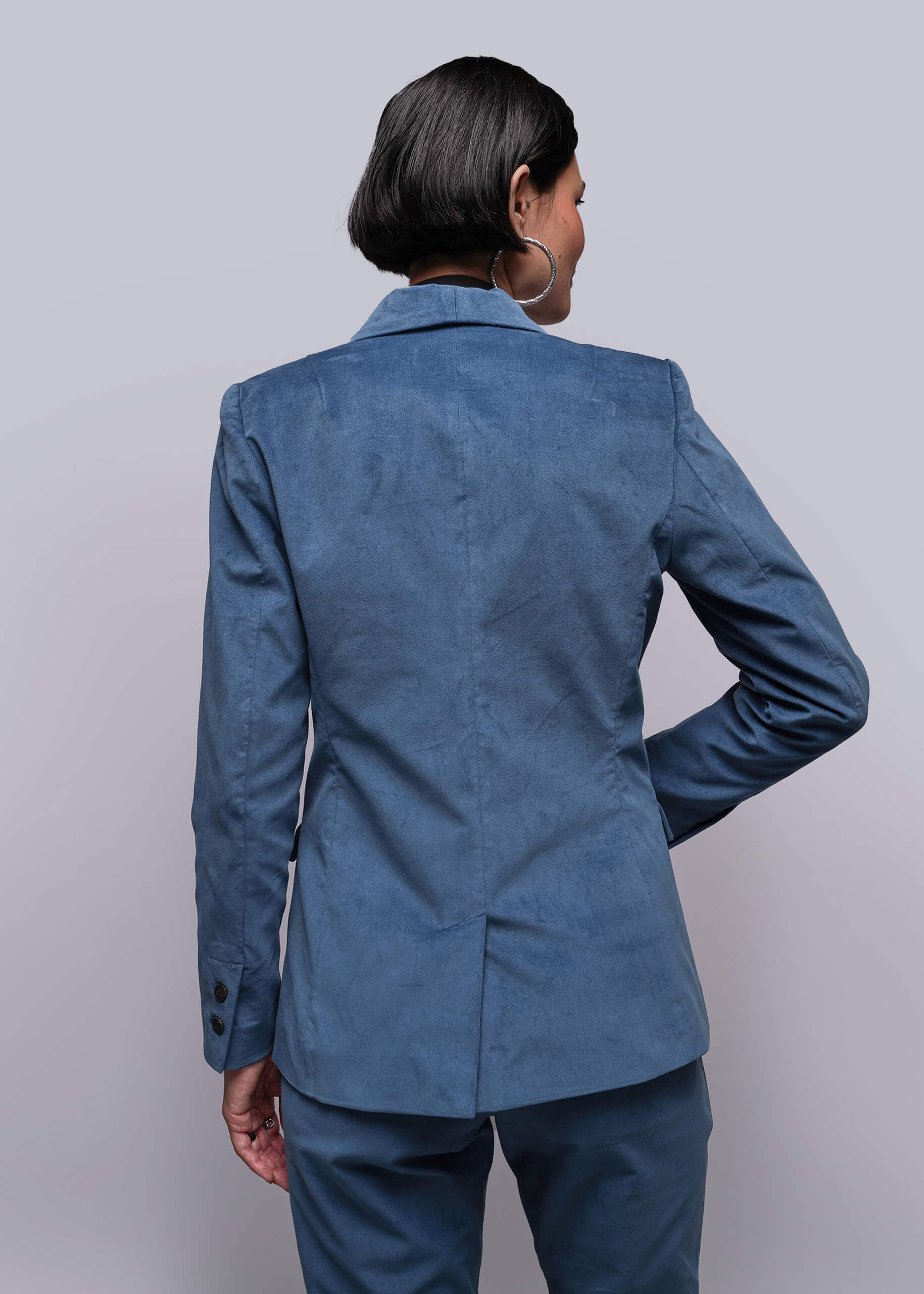 S=Person wearing a blue blazer and pants against a plain background