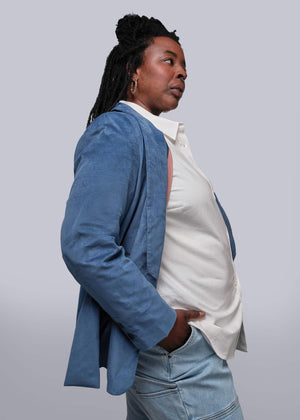 1X=Person wearing a blue blazer over a white shirt on a plain background