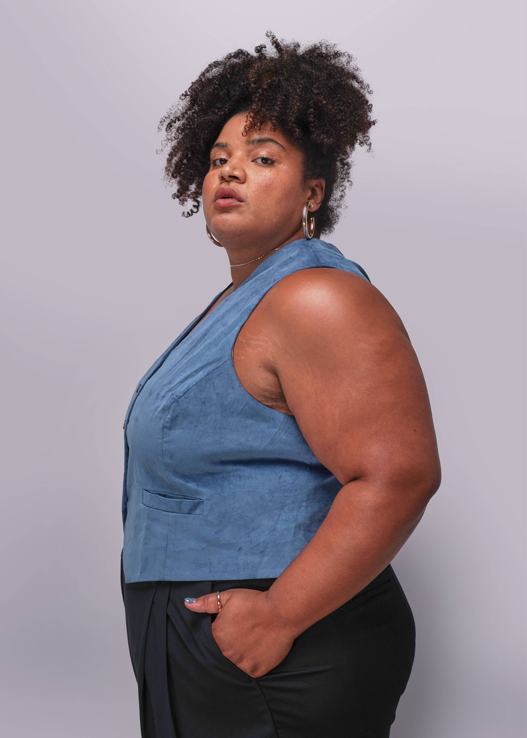 1X=Person wearing a blue sleeveless top against a plain background