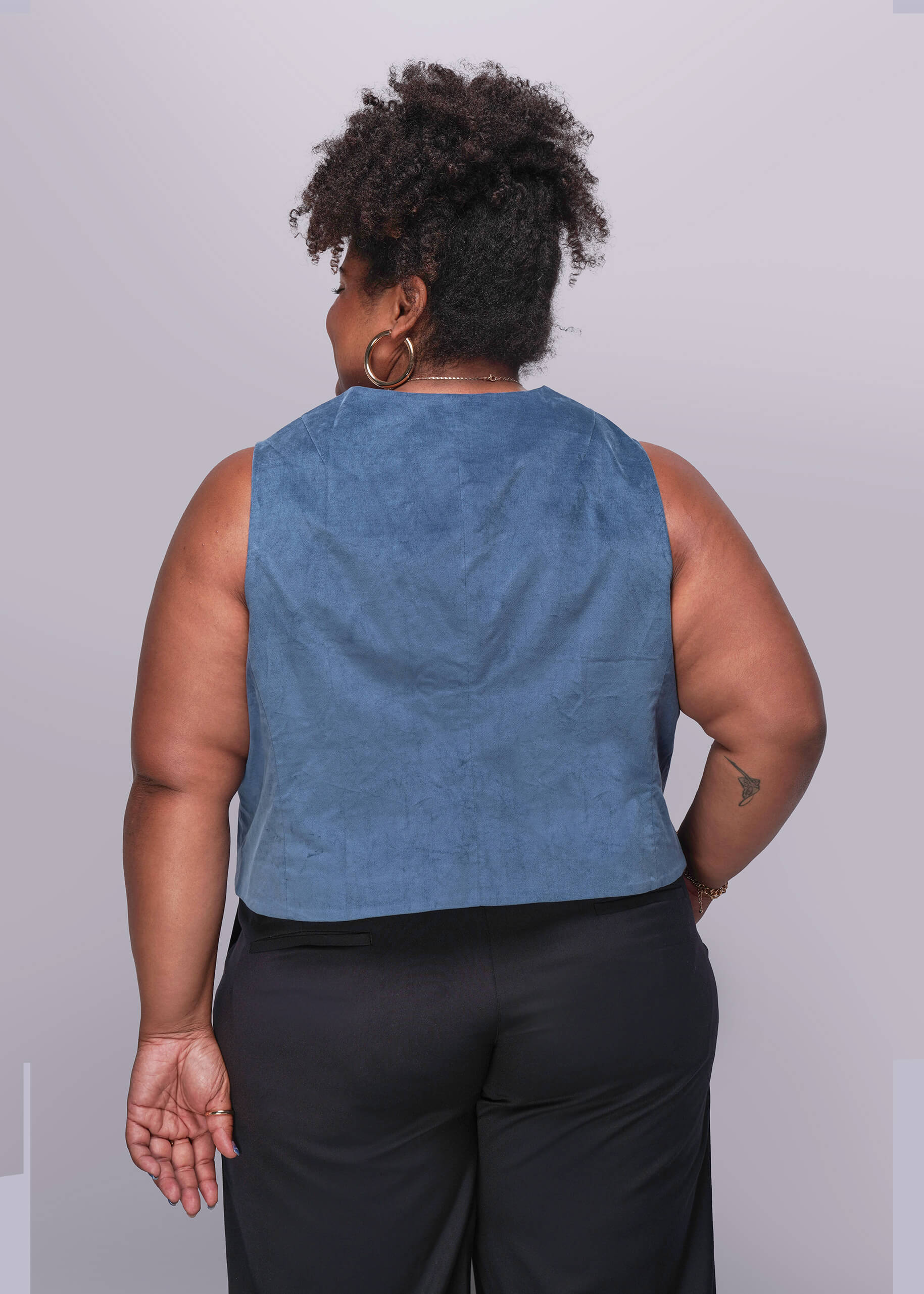 1X=Person wearing a blue velvet vest and black pants against a plain background