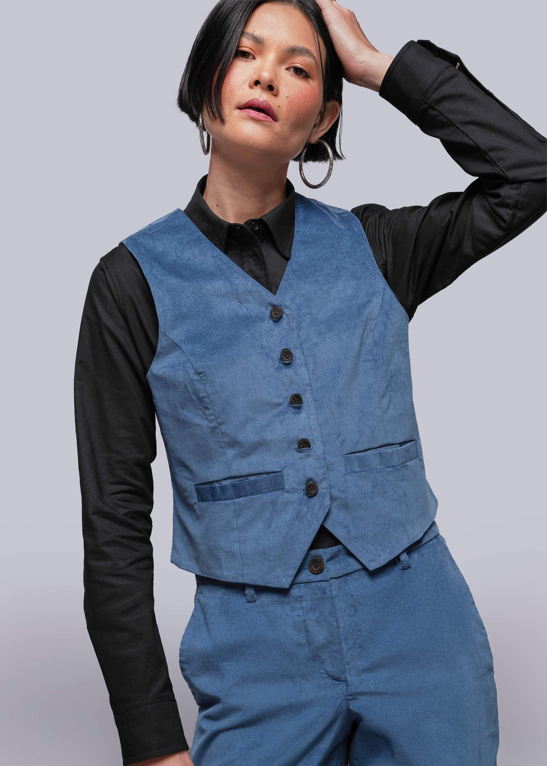S=Person wearing a blue vest over a black shirt on a plain background