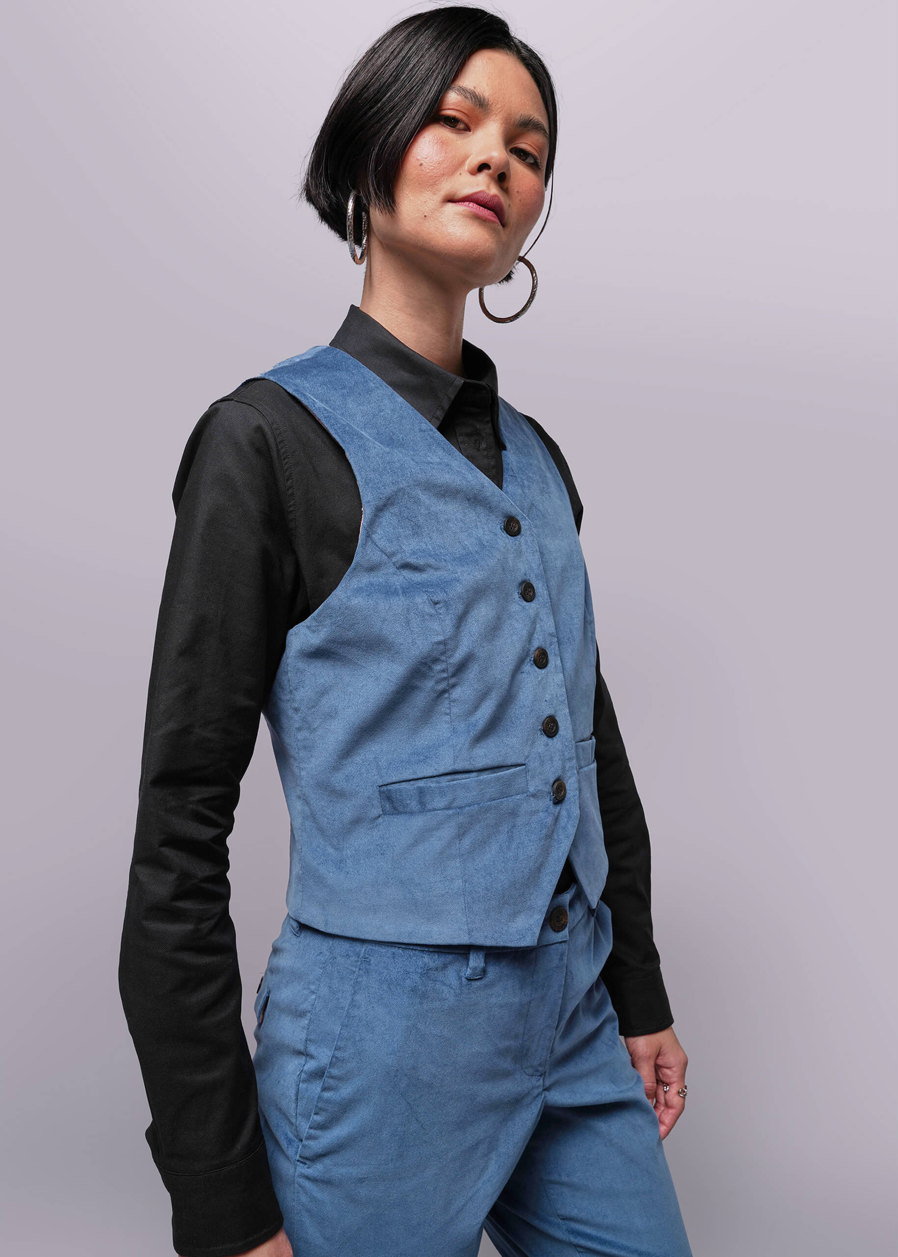 S=Person wearing a blue vest over a black shirt on a plain background