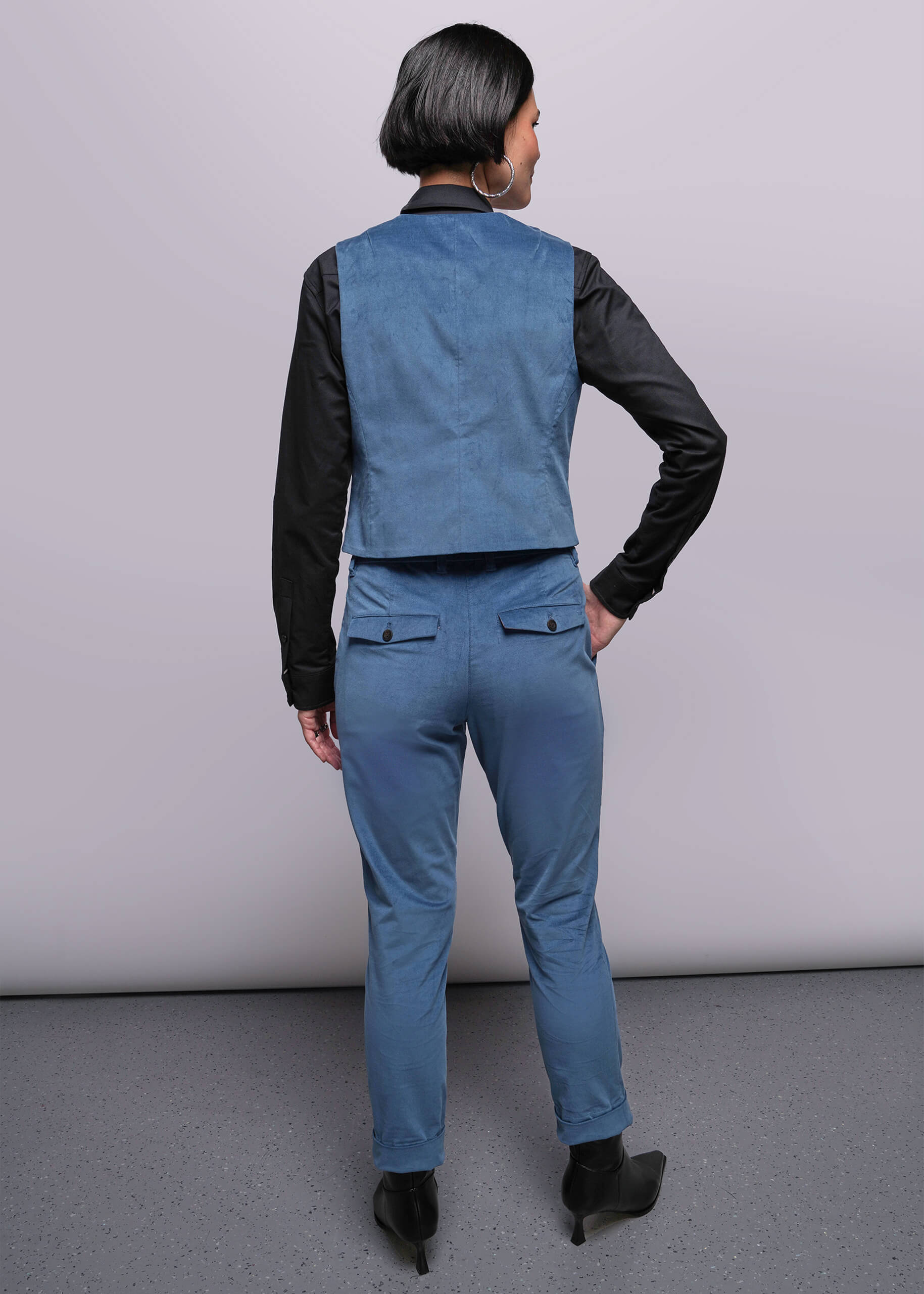S=Person wearing a blue vest and pants with black sleeves against a plain background