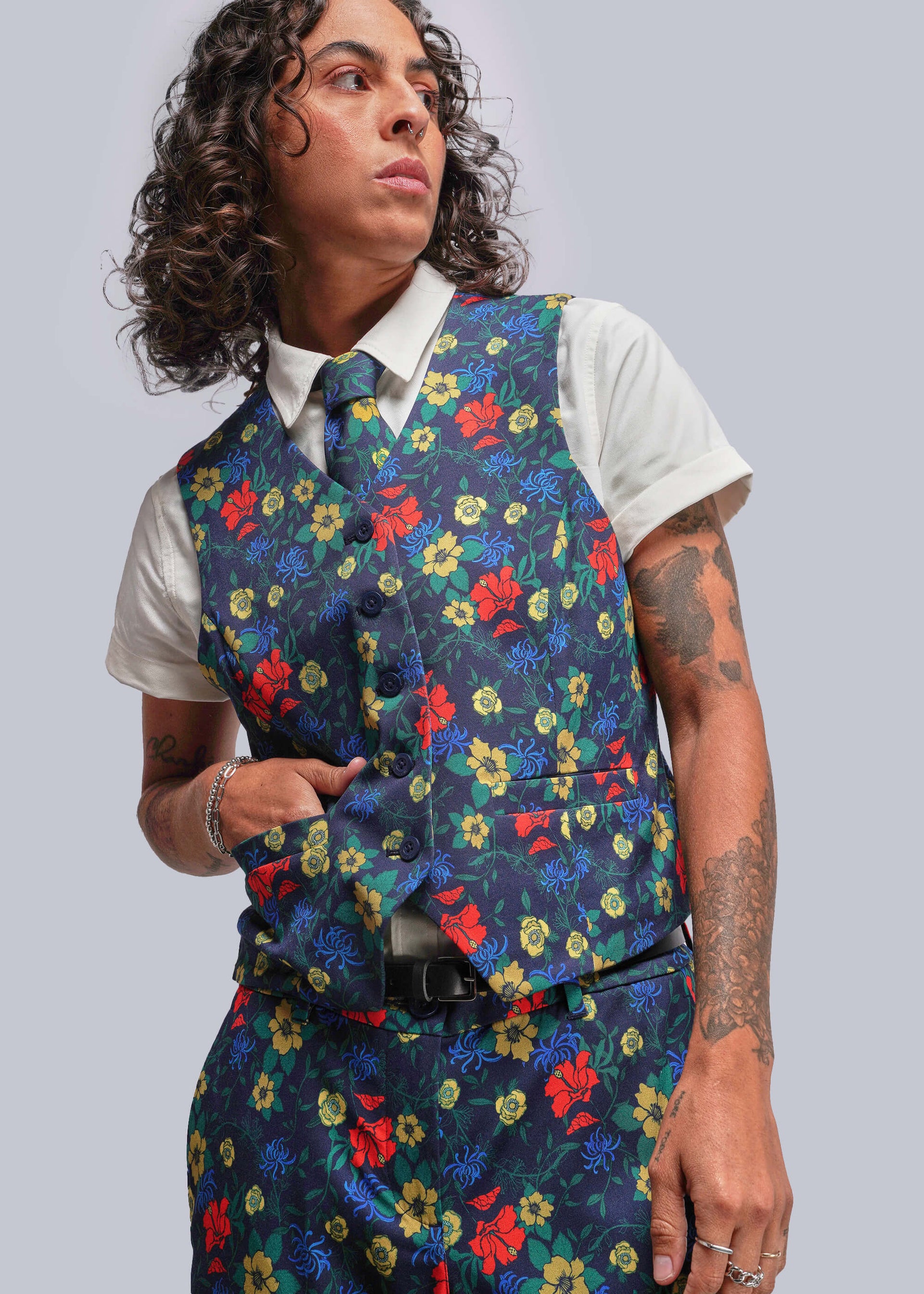 S=Person wearing a colorful floral vest over a white shirt on a gray background