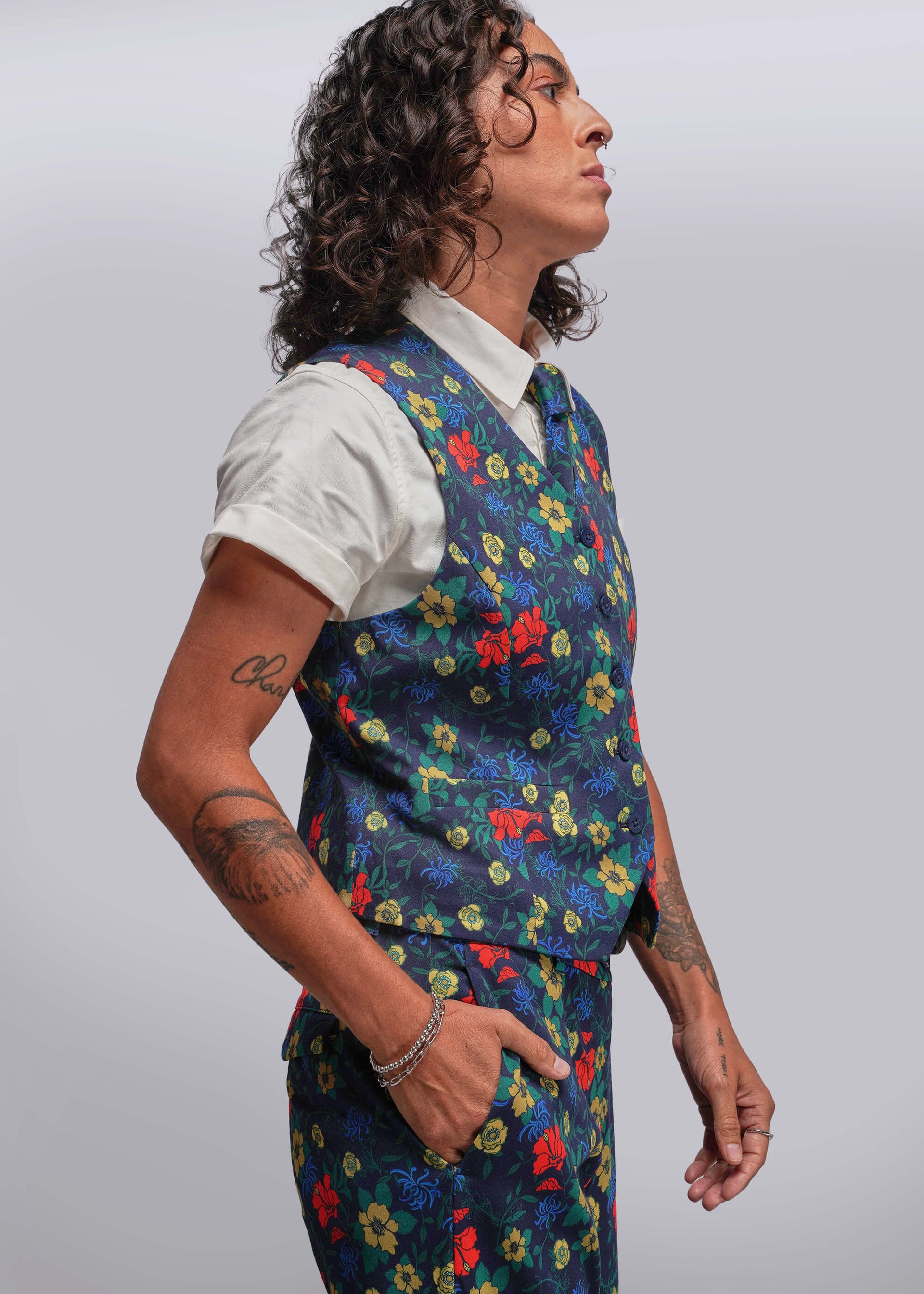 S=Person wearing a colorful floral vest over a white shirt on a plain background