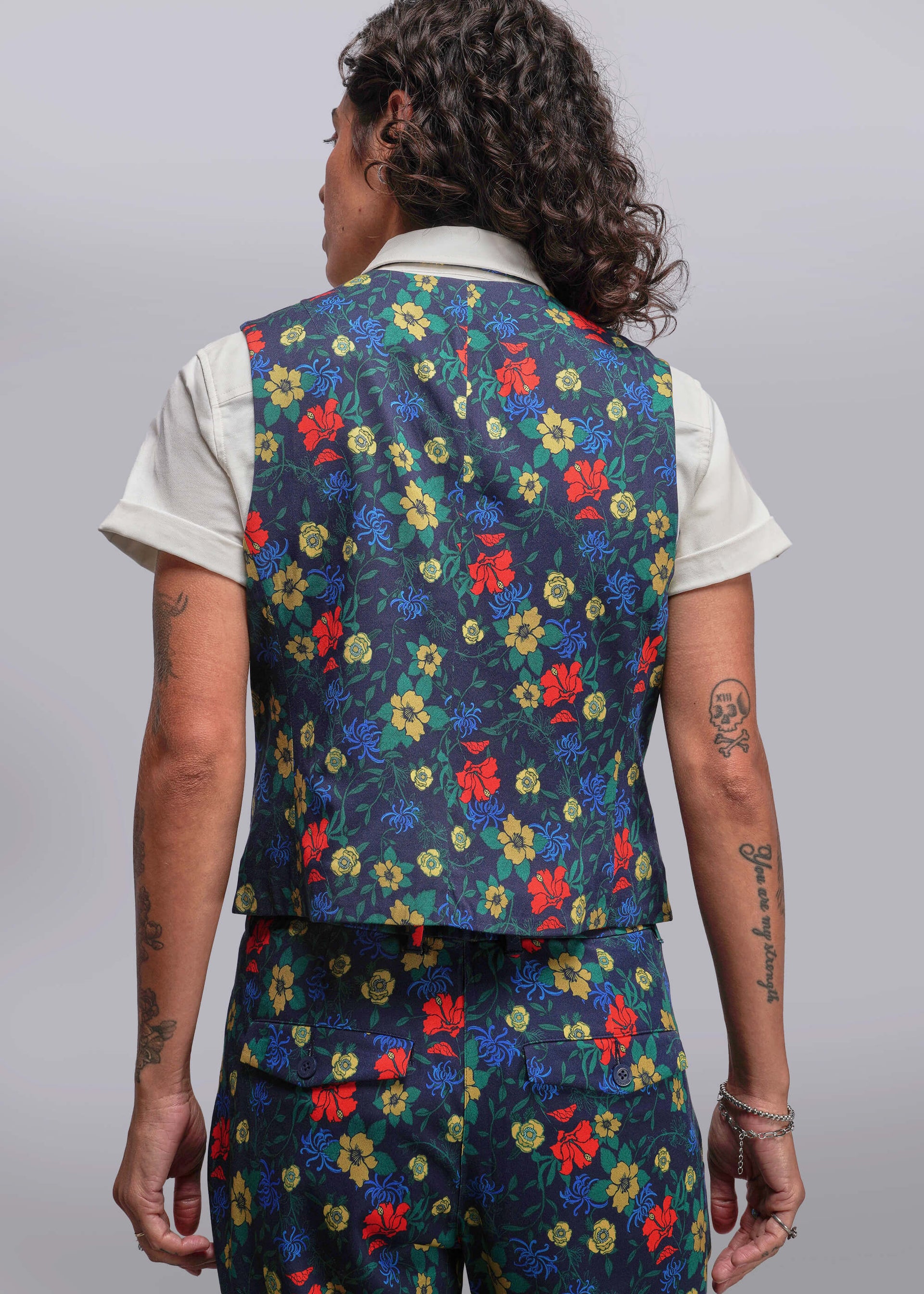 S=Person wearing a colorful floral vest and pants on a plain background