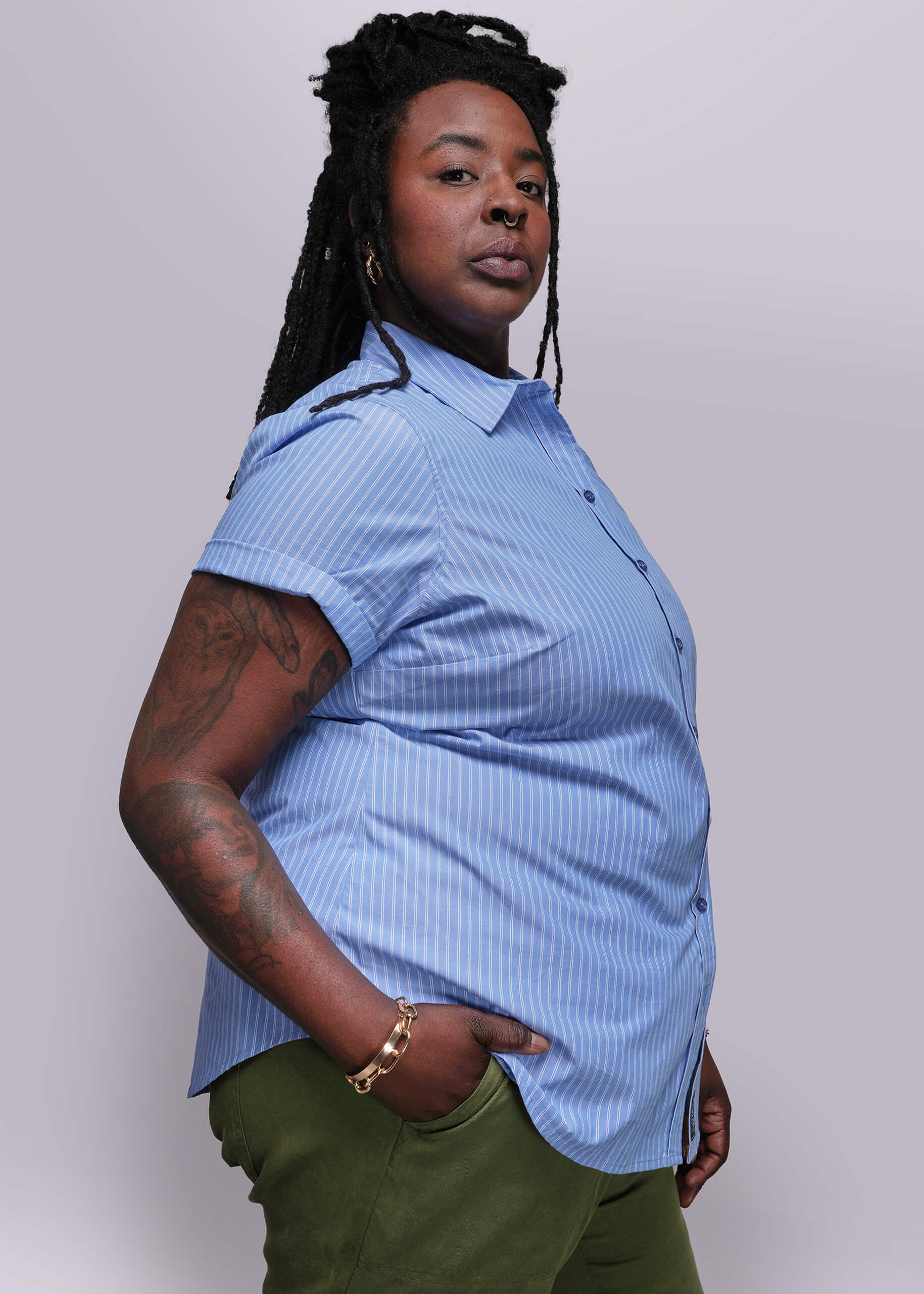 1X=Person wearing a blue short-sleeve shirt and green pants against a plain background