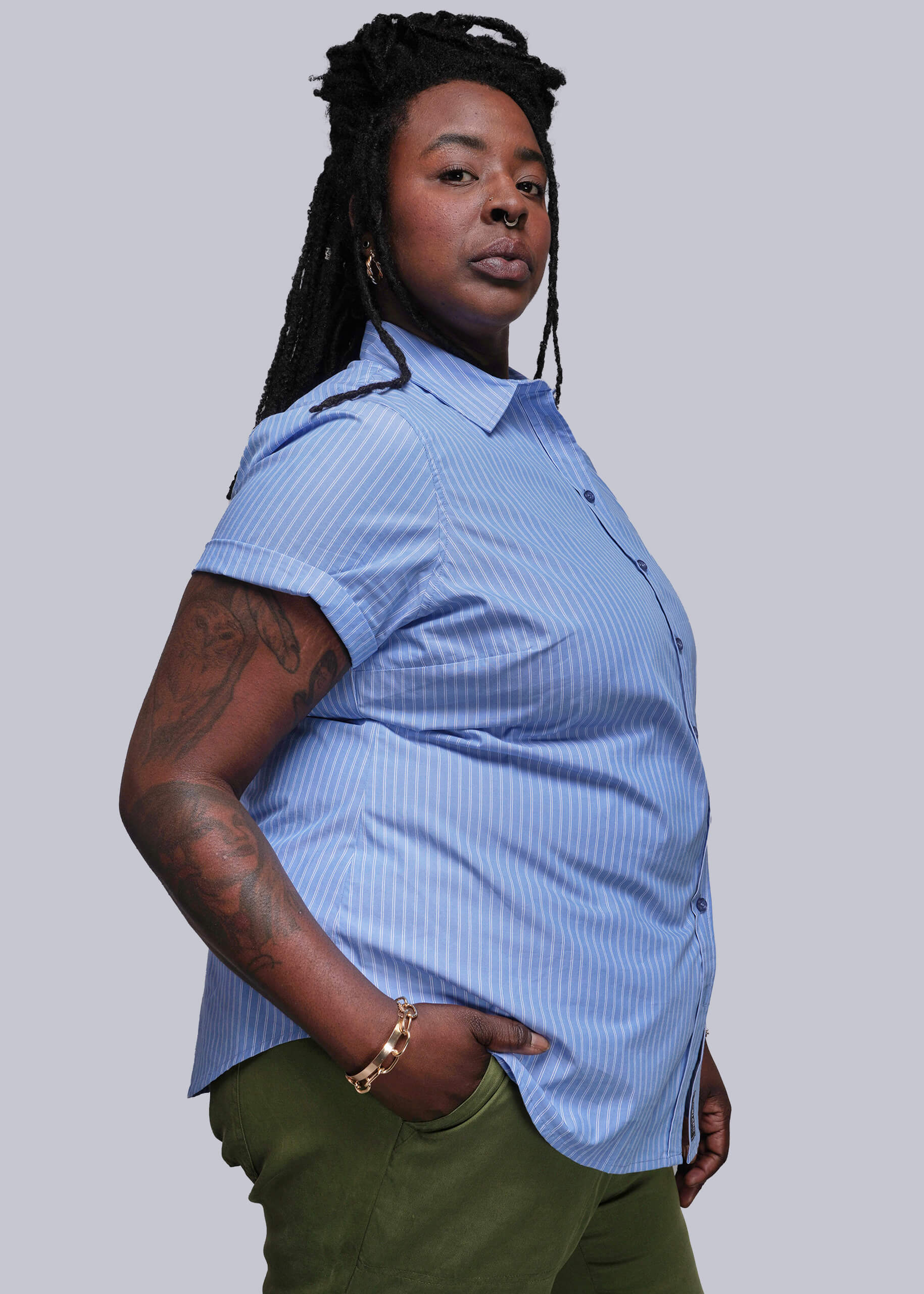 1X=Person wearing a blue short-sleeve shirt and green pants against a plain background