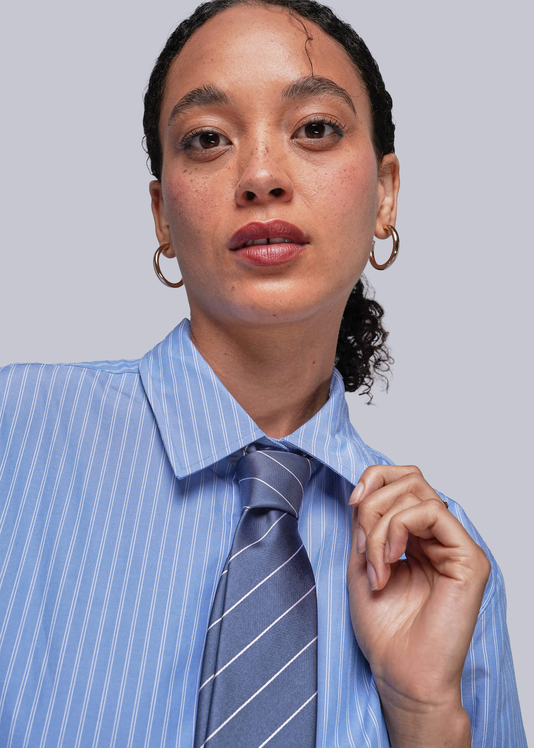 S=Person wearing a blue striped shirt and tie against a plain background