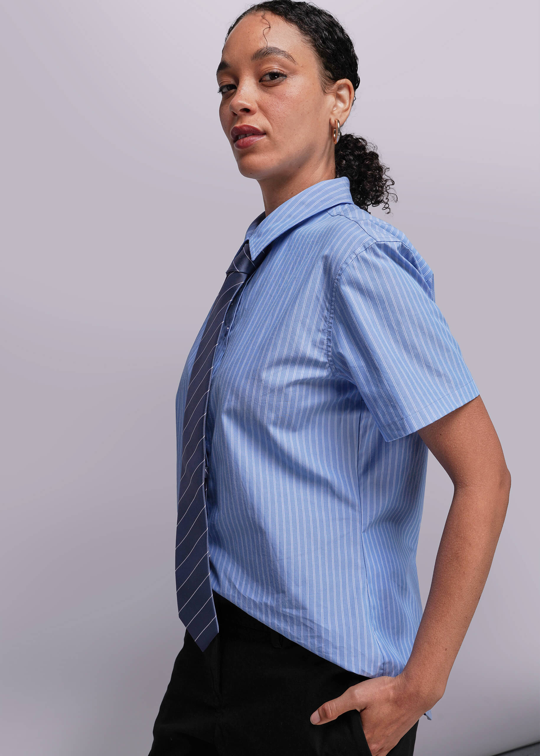 S=Side view of person wearing a blue striped shirt with a tie against a plain background