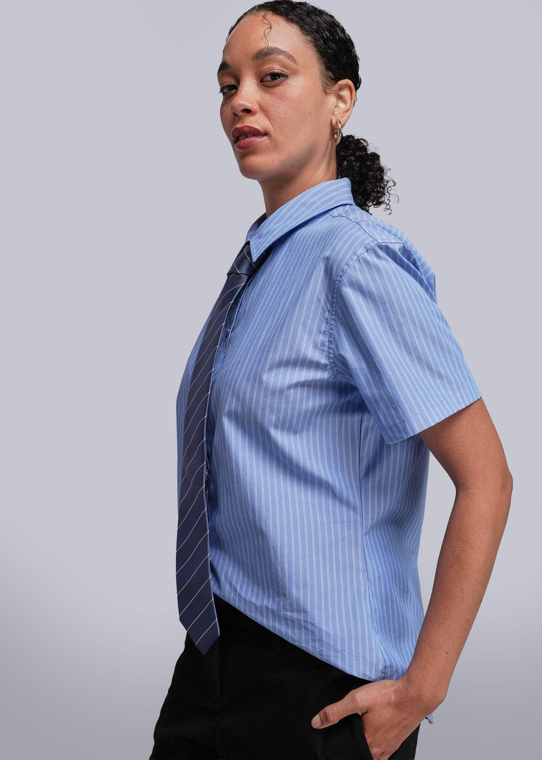 S=Side view of person wearing a blue striped shirt with a tie against a plain background