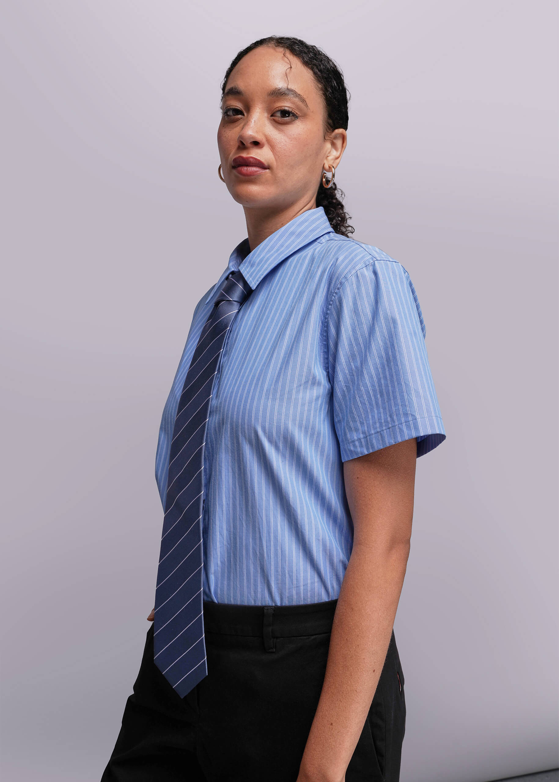 S=Person wearing a blue striped shirt with a striped tie against a plain background