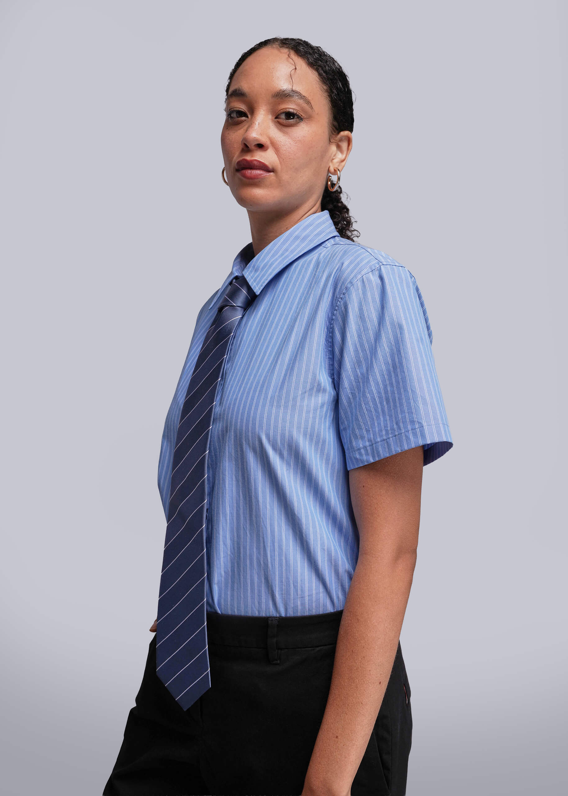 S=Person wearing a blue striped shirt with a striped tie against a plain background