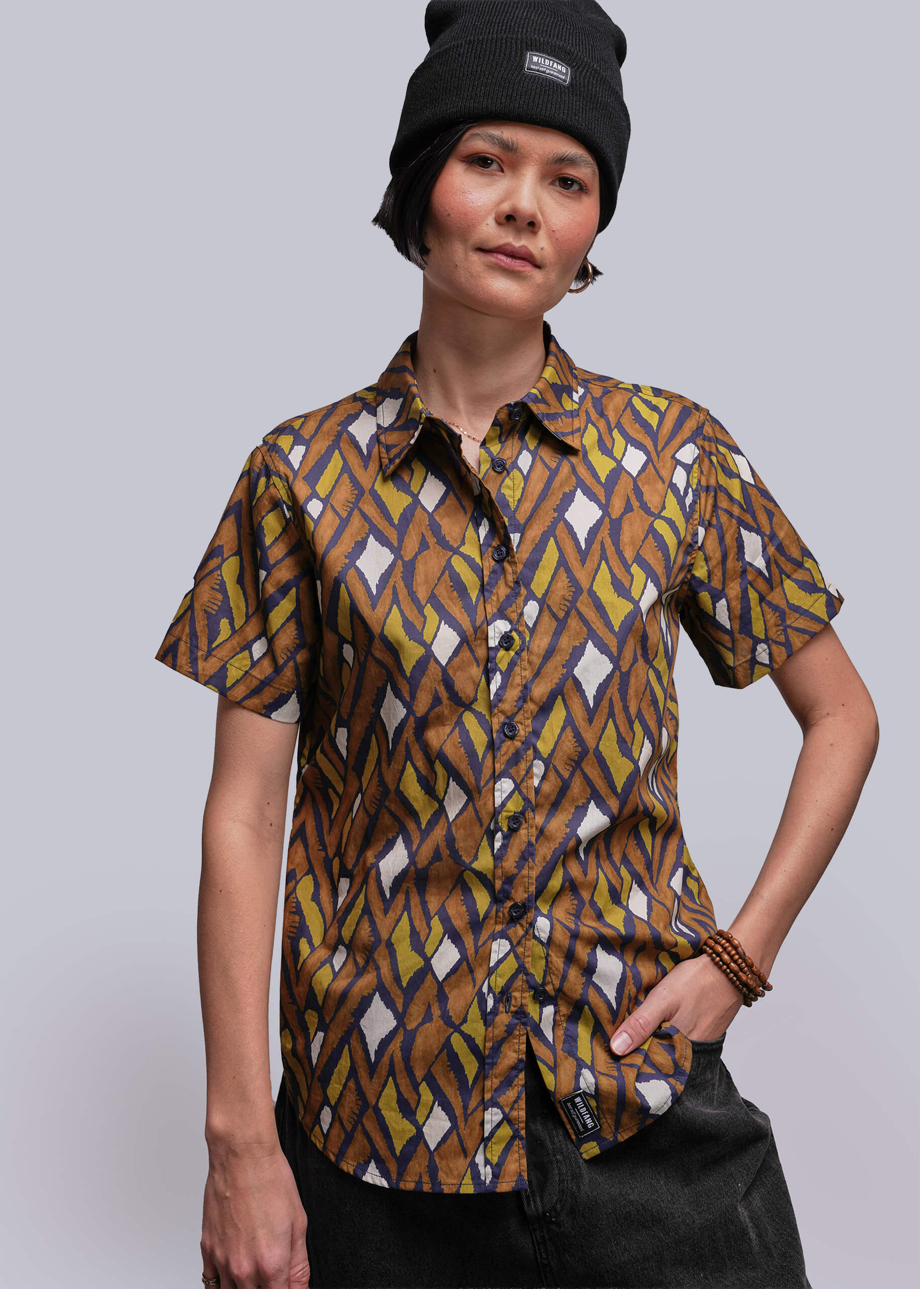 S=Person wearing a patterned button up shirt and black beanie against a plain background