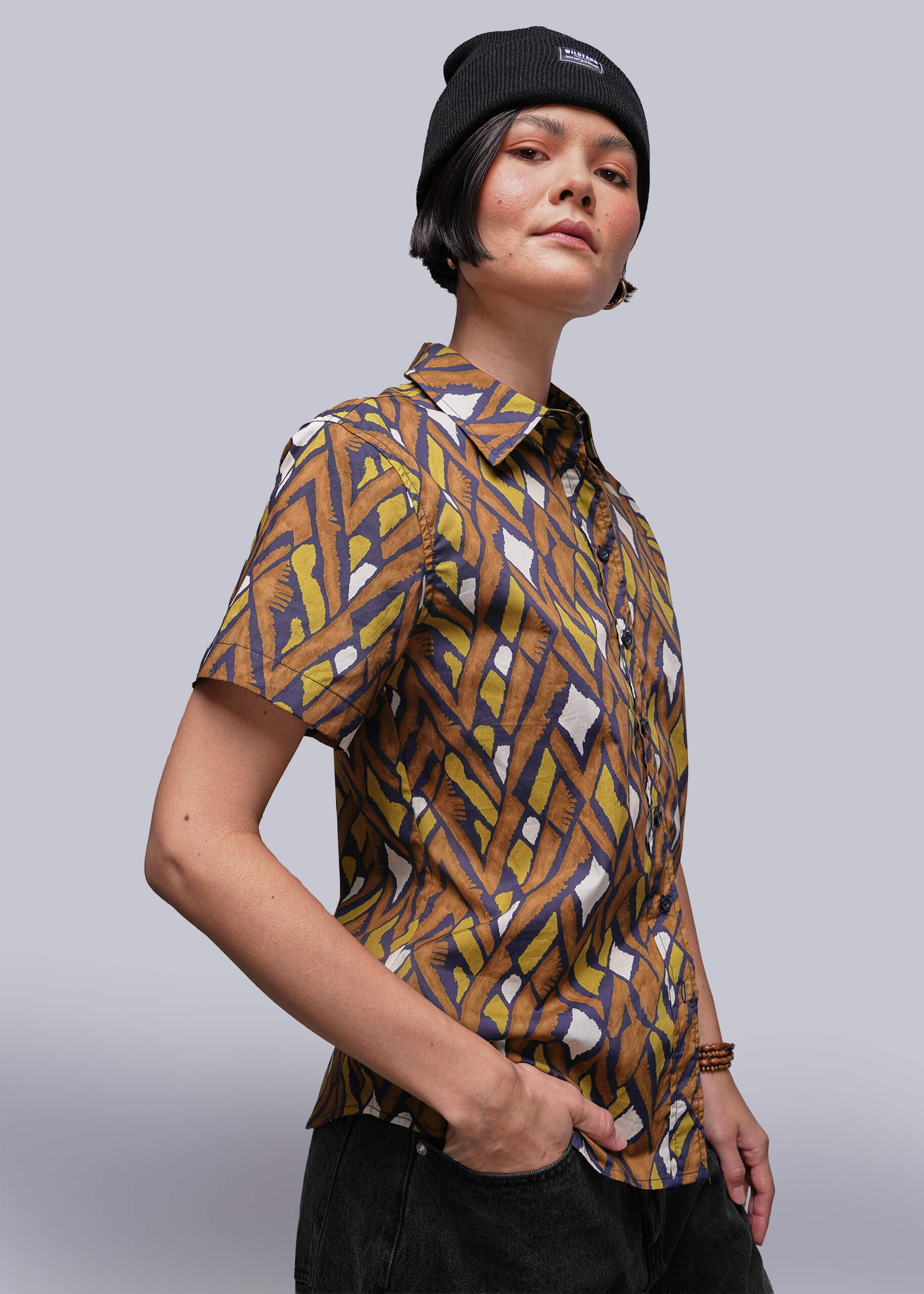 S=Person wearing a patterned shirt and black beanie against a plain background