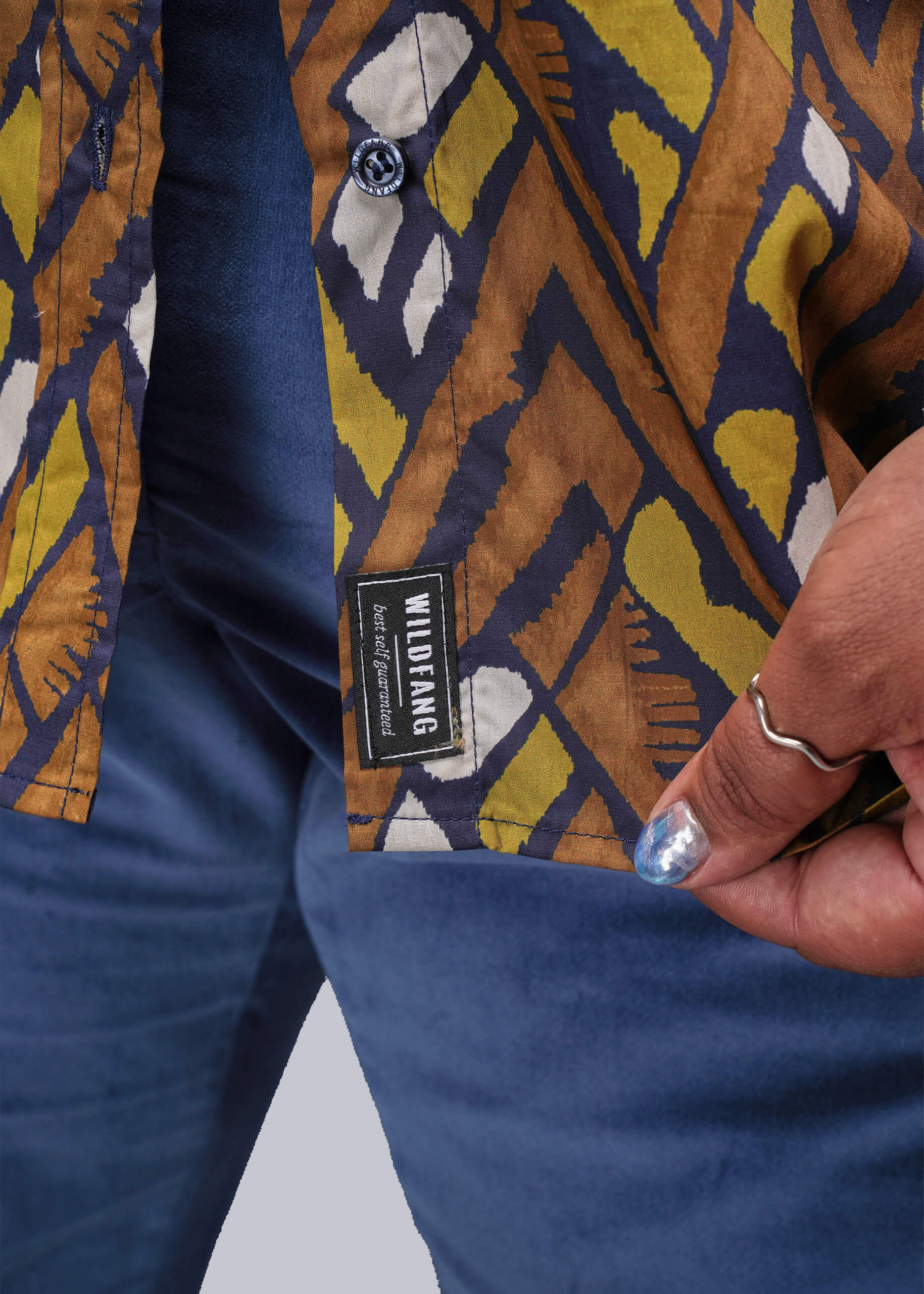 1X=Close-up of a patterned button up shirt with a visible brand label on a plain background