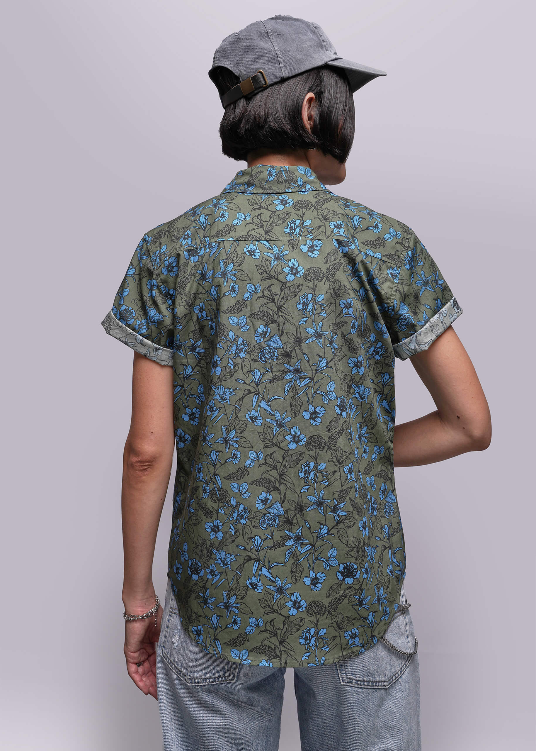 S=Person wearing a green floral patterned shirt and gray cap on a plain background