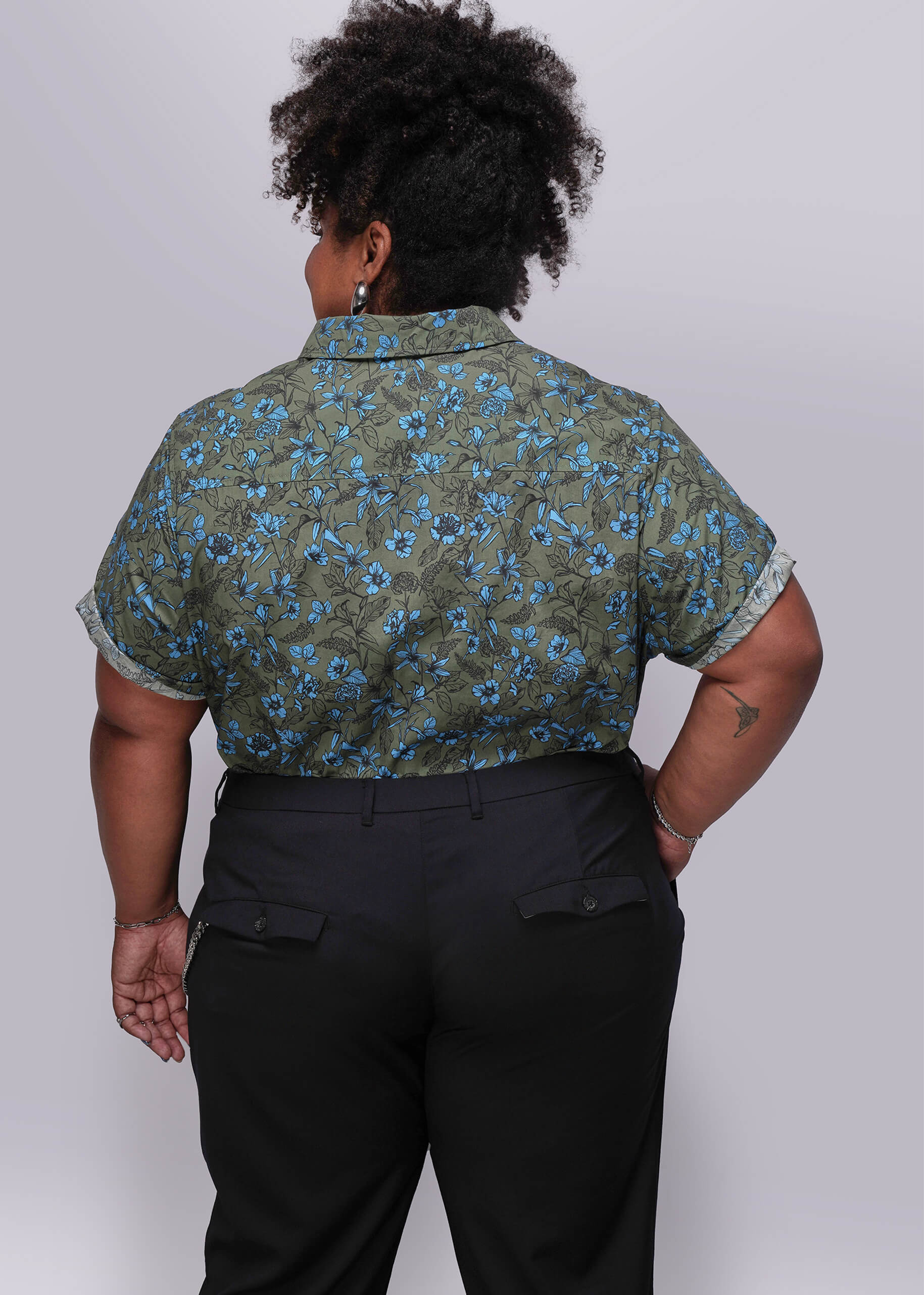 1X=Person wearing a green floral shirt and black pants against a white background