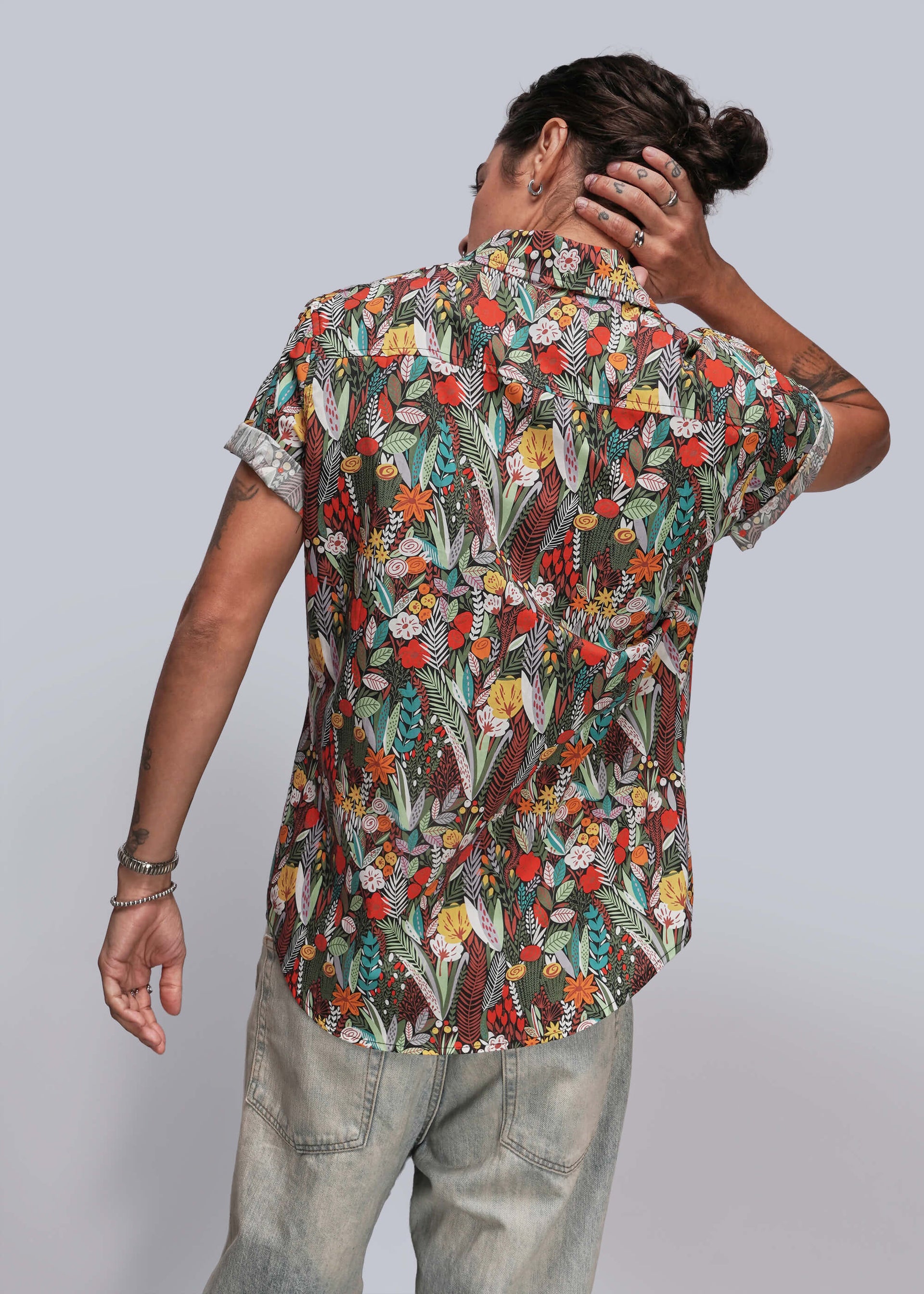 S=Person wearing a colorful floral shirt with their back to the camera on a light gray background