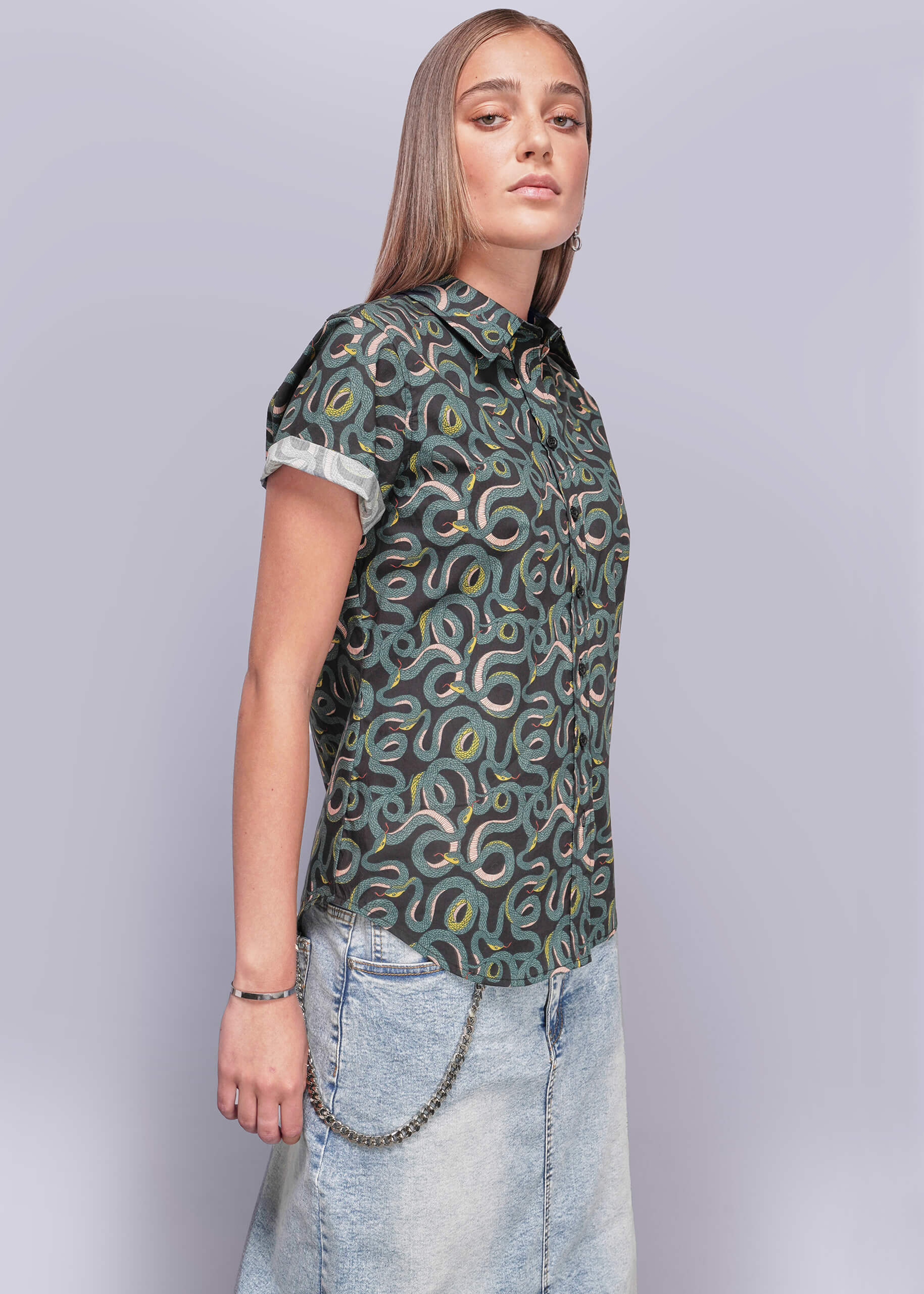 S=Woman wearing a patterned shirt and jeans on a plain background