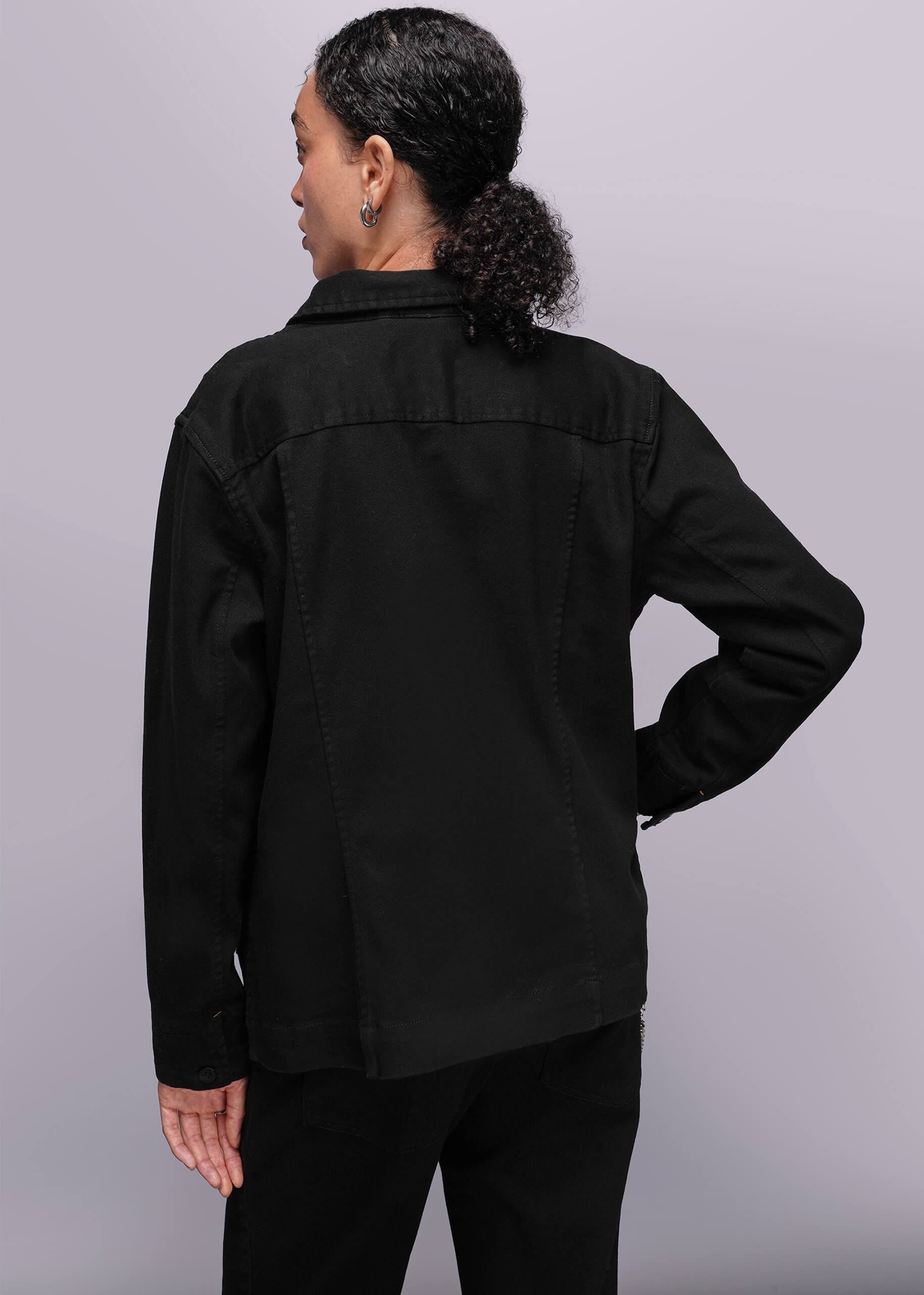 S=Back of person wearing a black jacket on a gray background