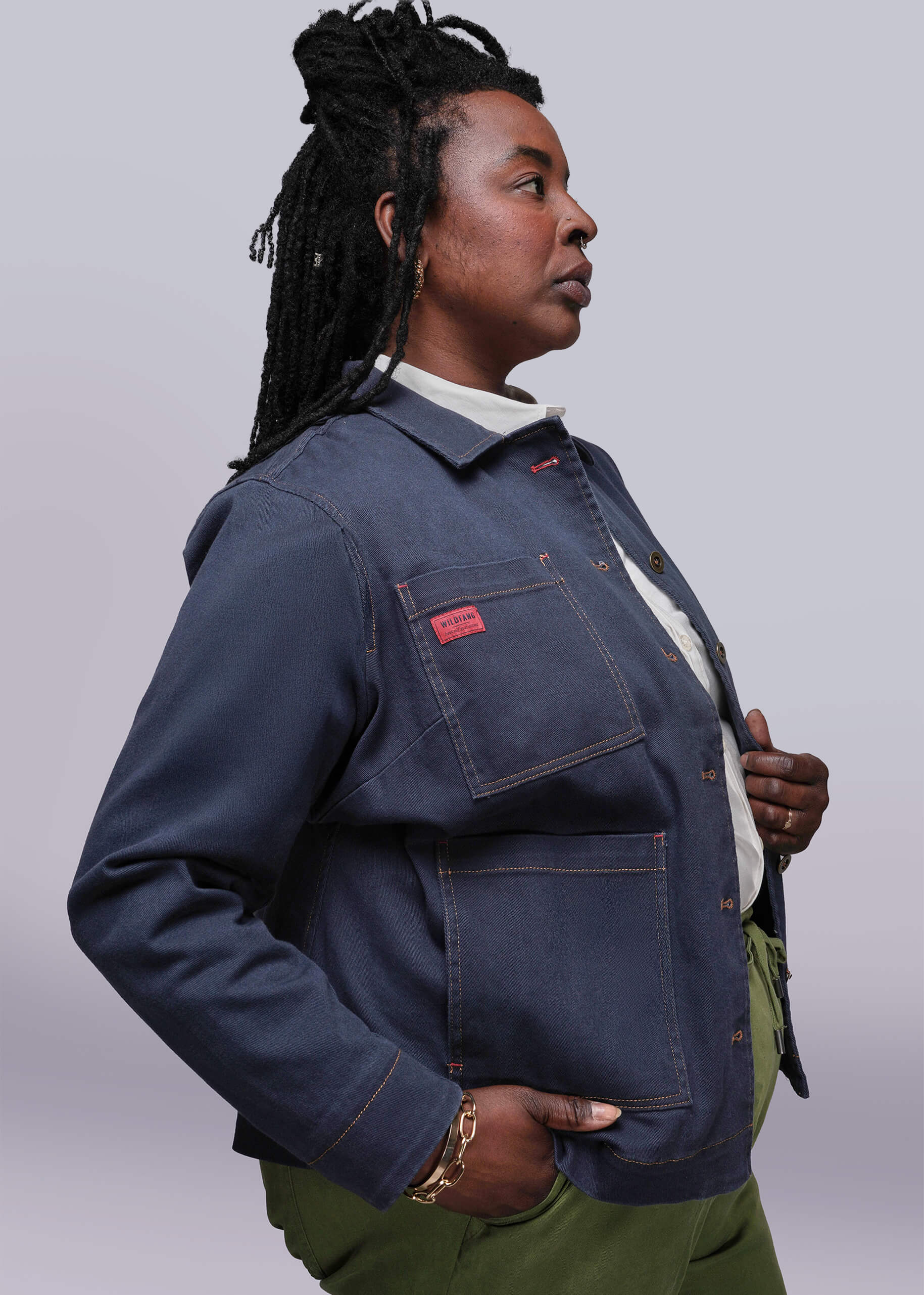 1X=Person wearing a blue denim jacket with a red label on a plain background