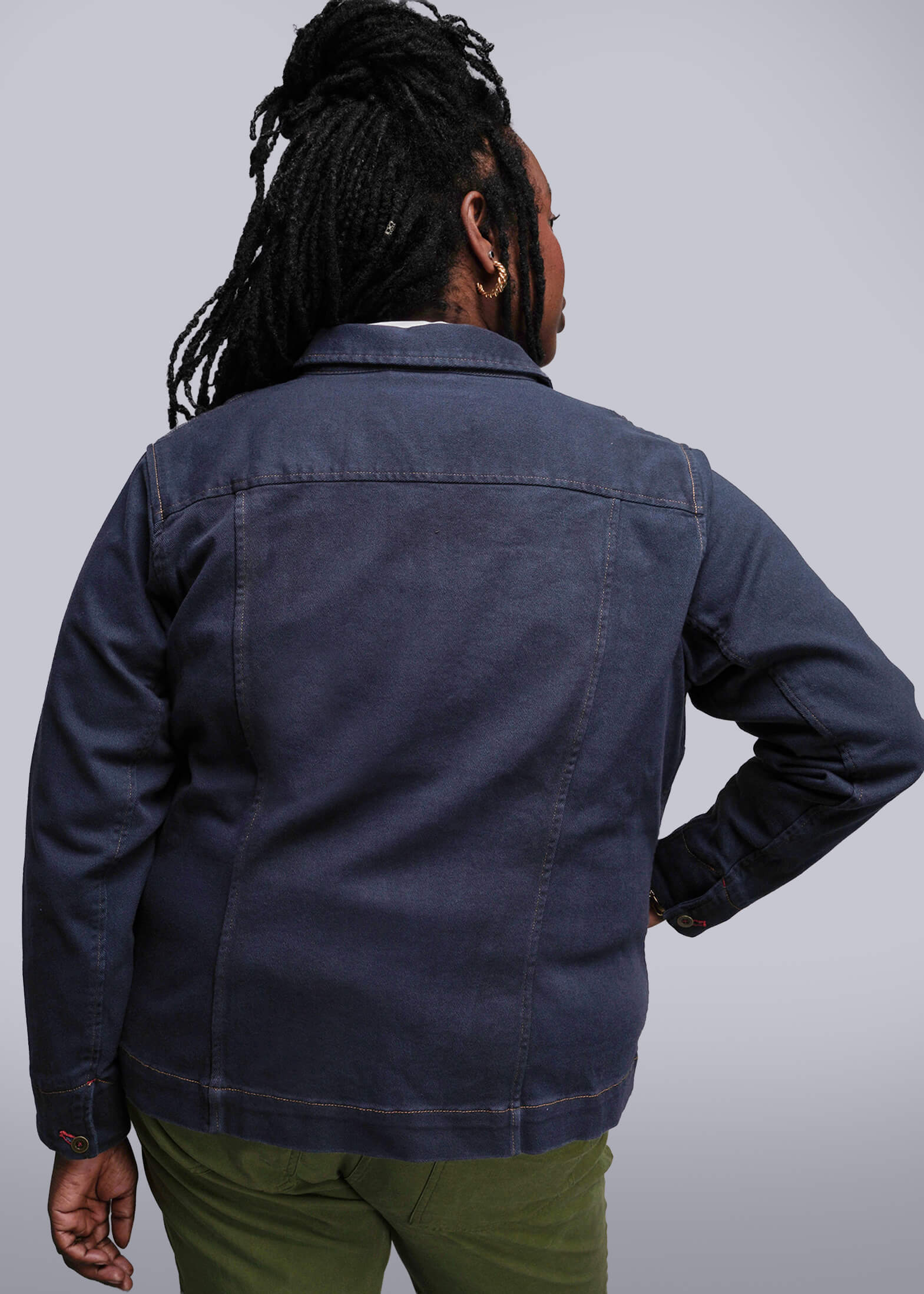 1X=Person wearing a blue jacket and green pants against a plain background