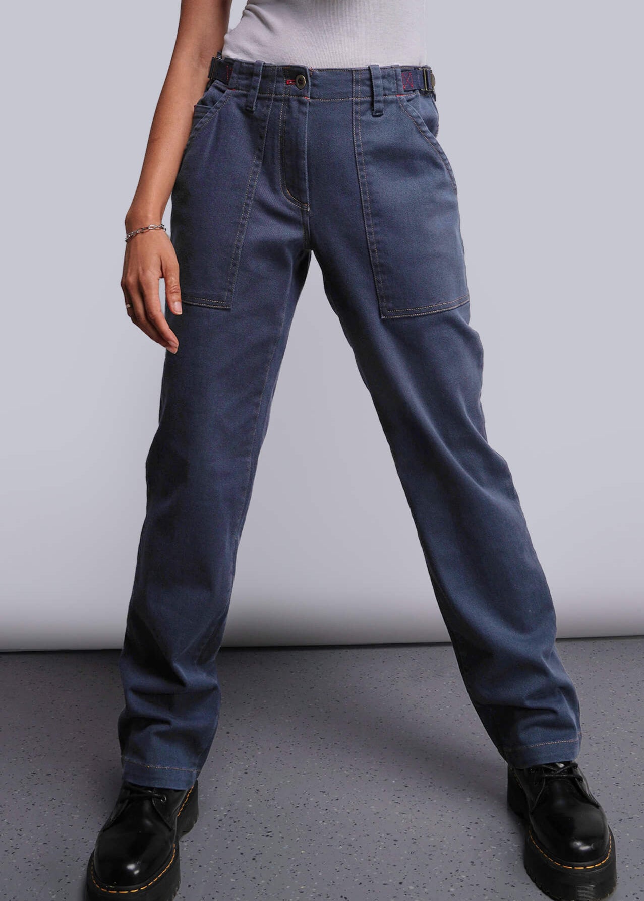 S=Person wearing blue jeans and black shoes on a plain background