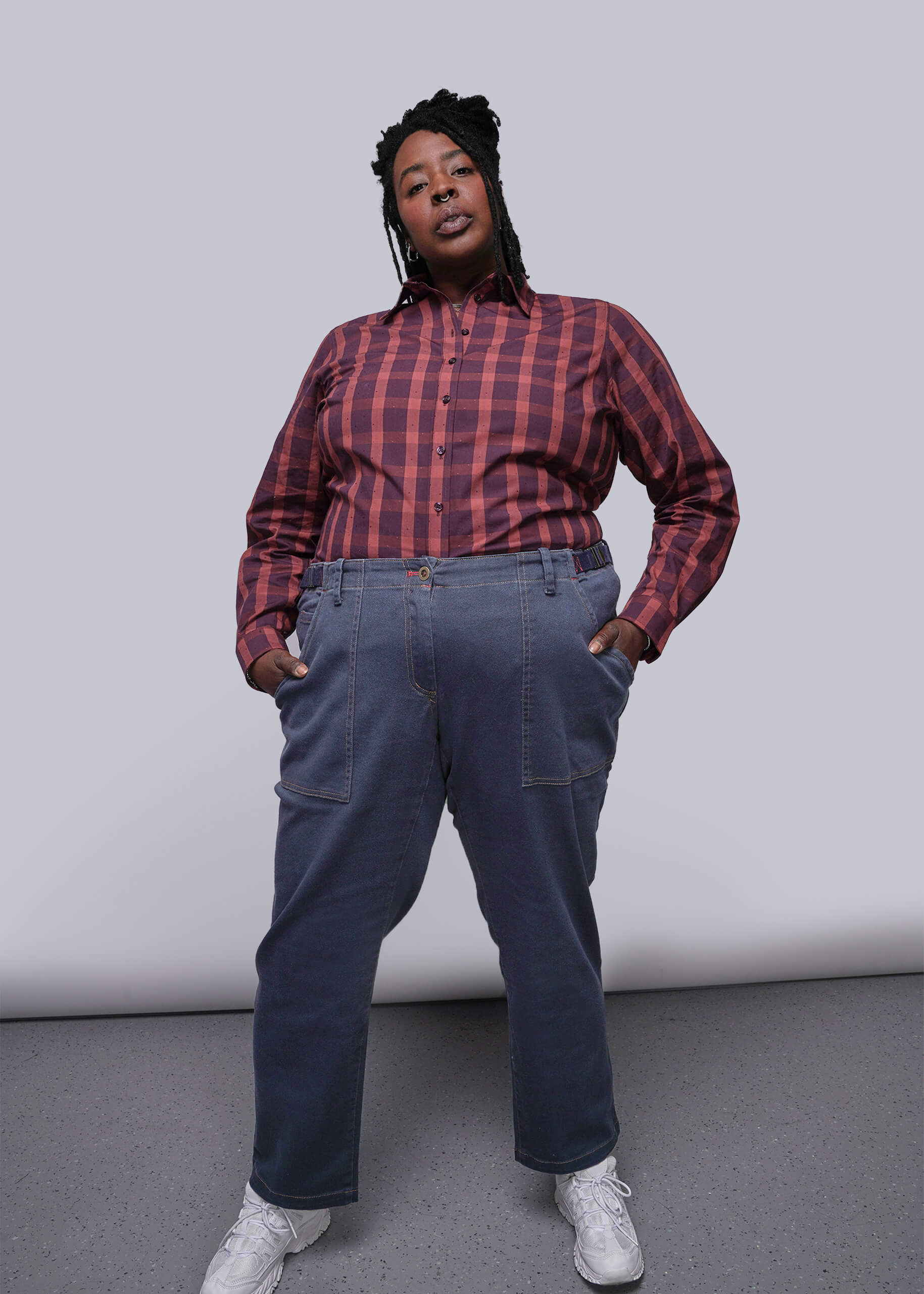 1X=Person wearing a red plaid shirt and blue jeans against a plain background