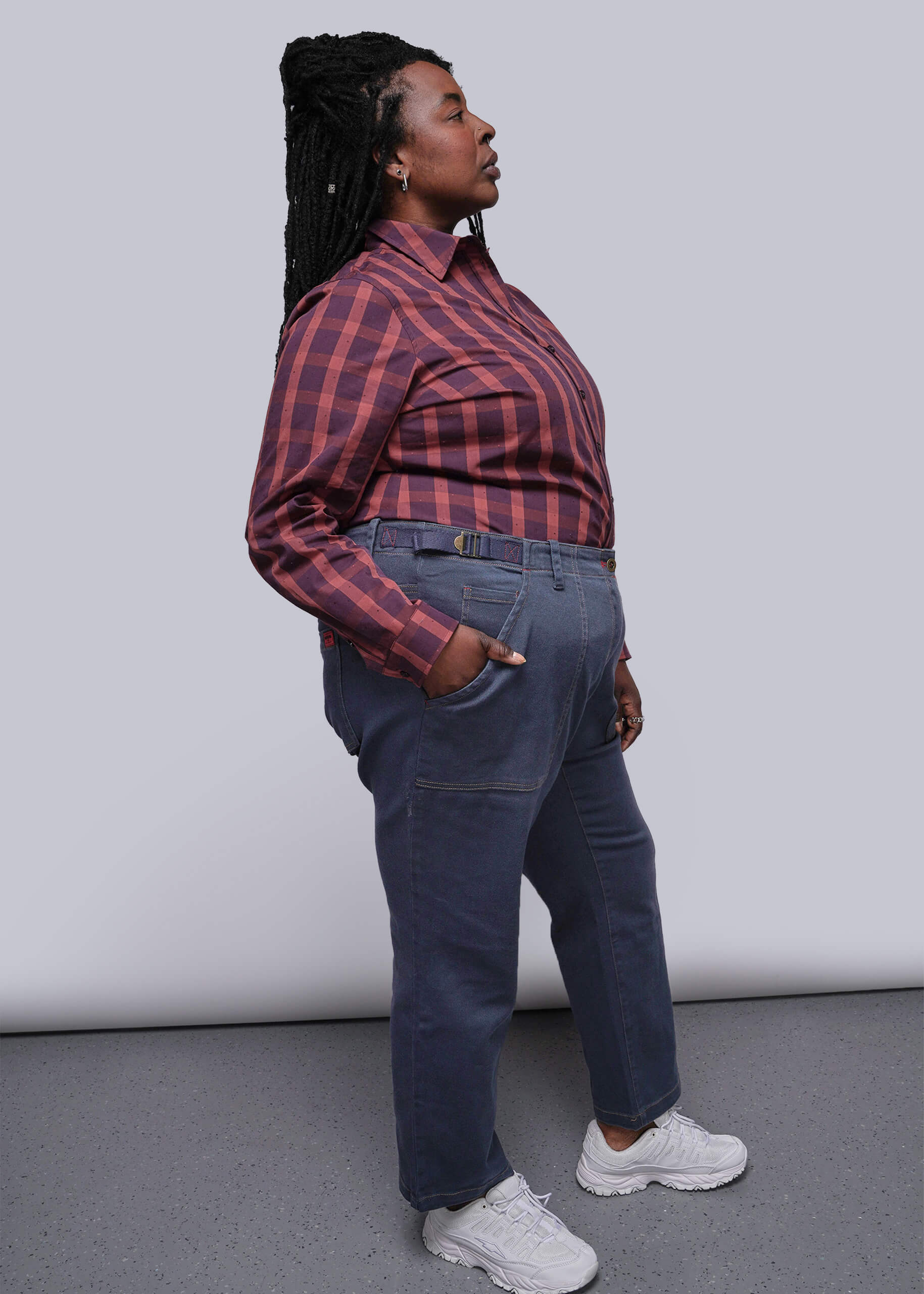 1X=Person wearing a red plaid shirt and blue jeans against a plain background