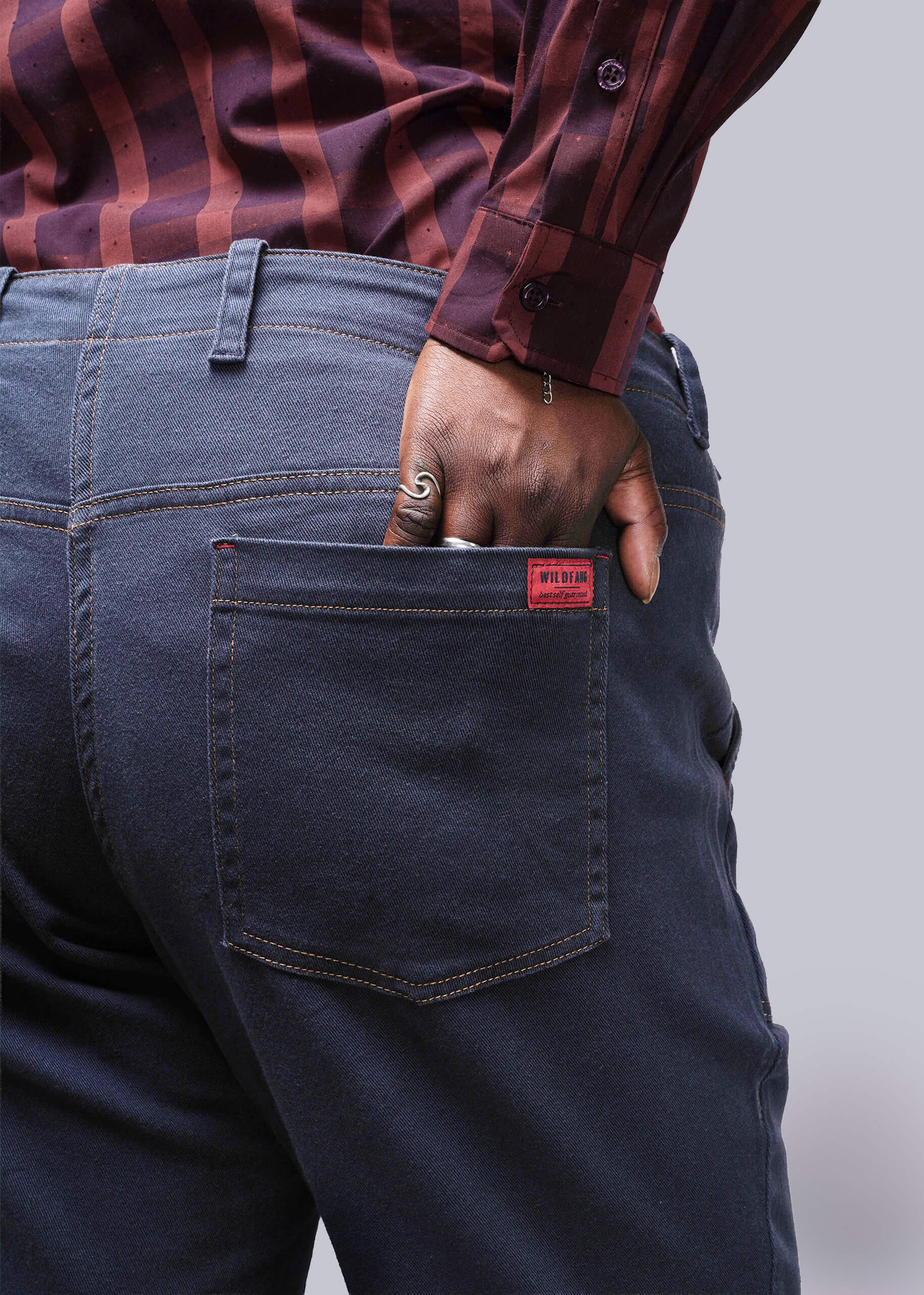 1X=Person wearing dark blue jeans with a red label on the pocket against a plain background