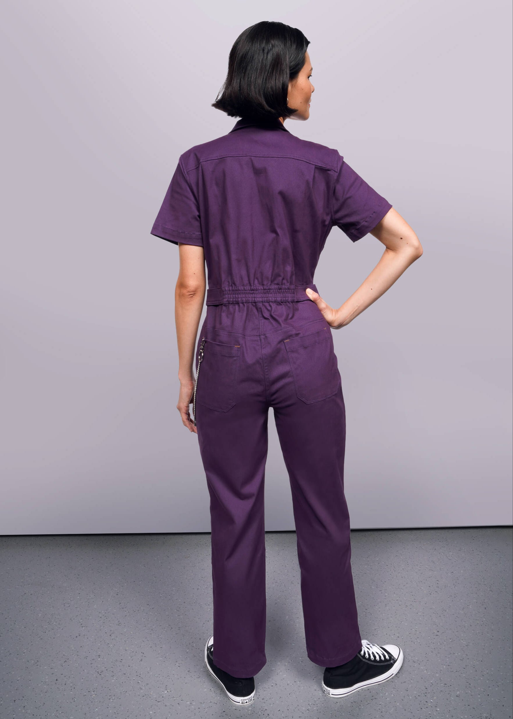 S=Person wearing a purple jumpsuit against a plain background