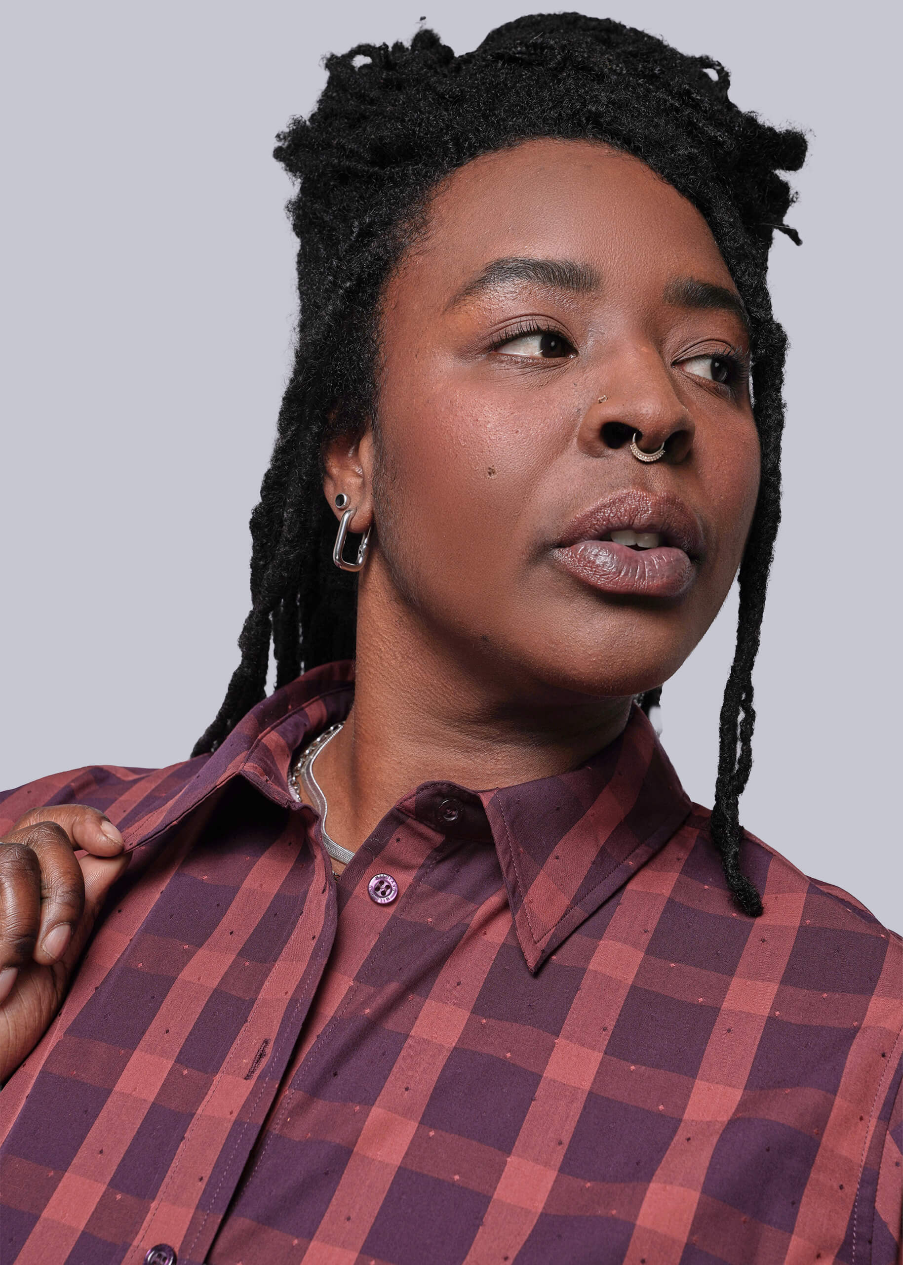 1X=Person wearing a red and brown plaid shirt against a plain background