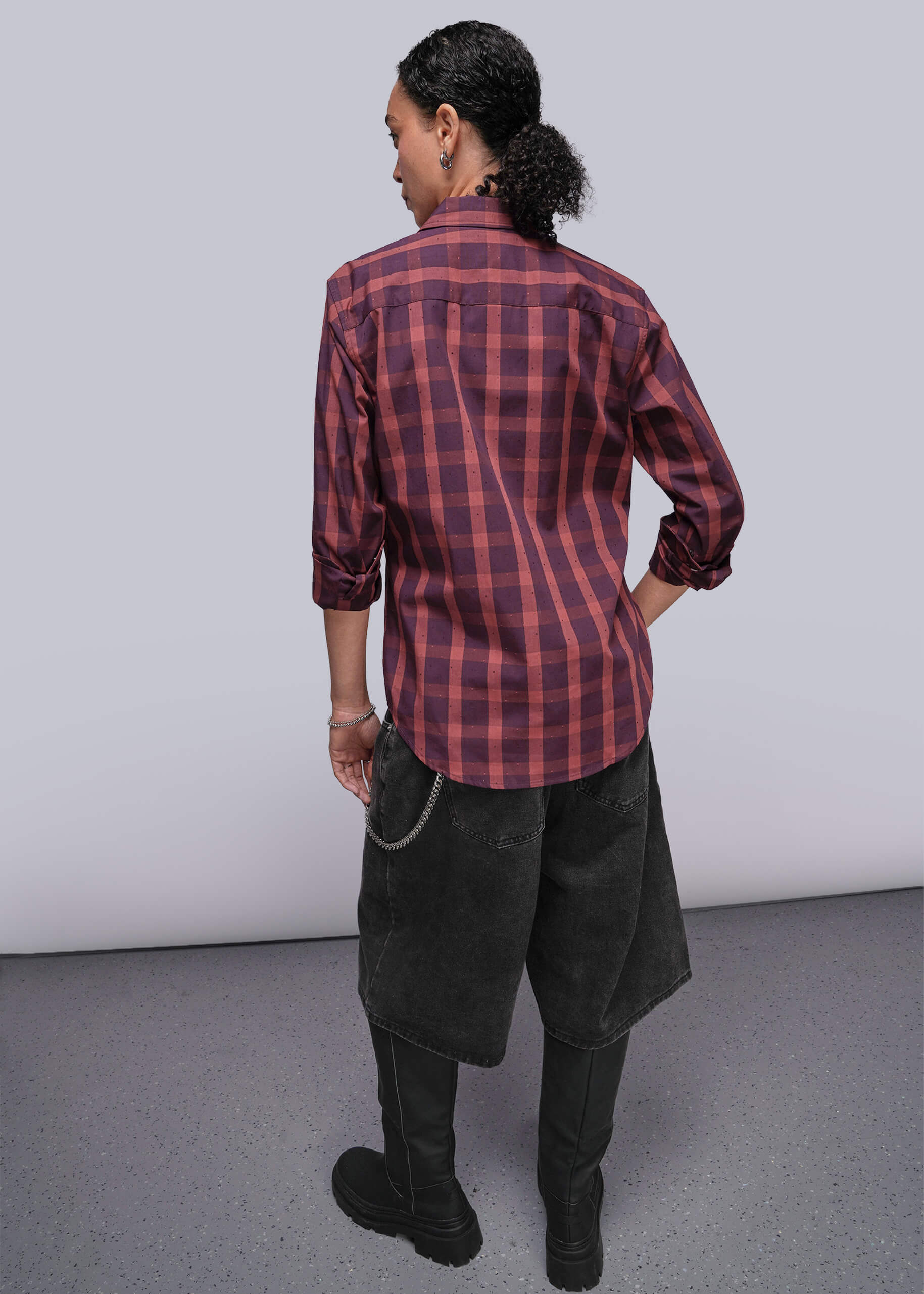 S=Person wearing a red plaid shirt with dark pants against a plain background