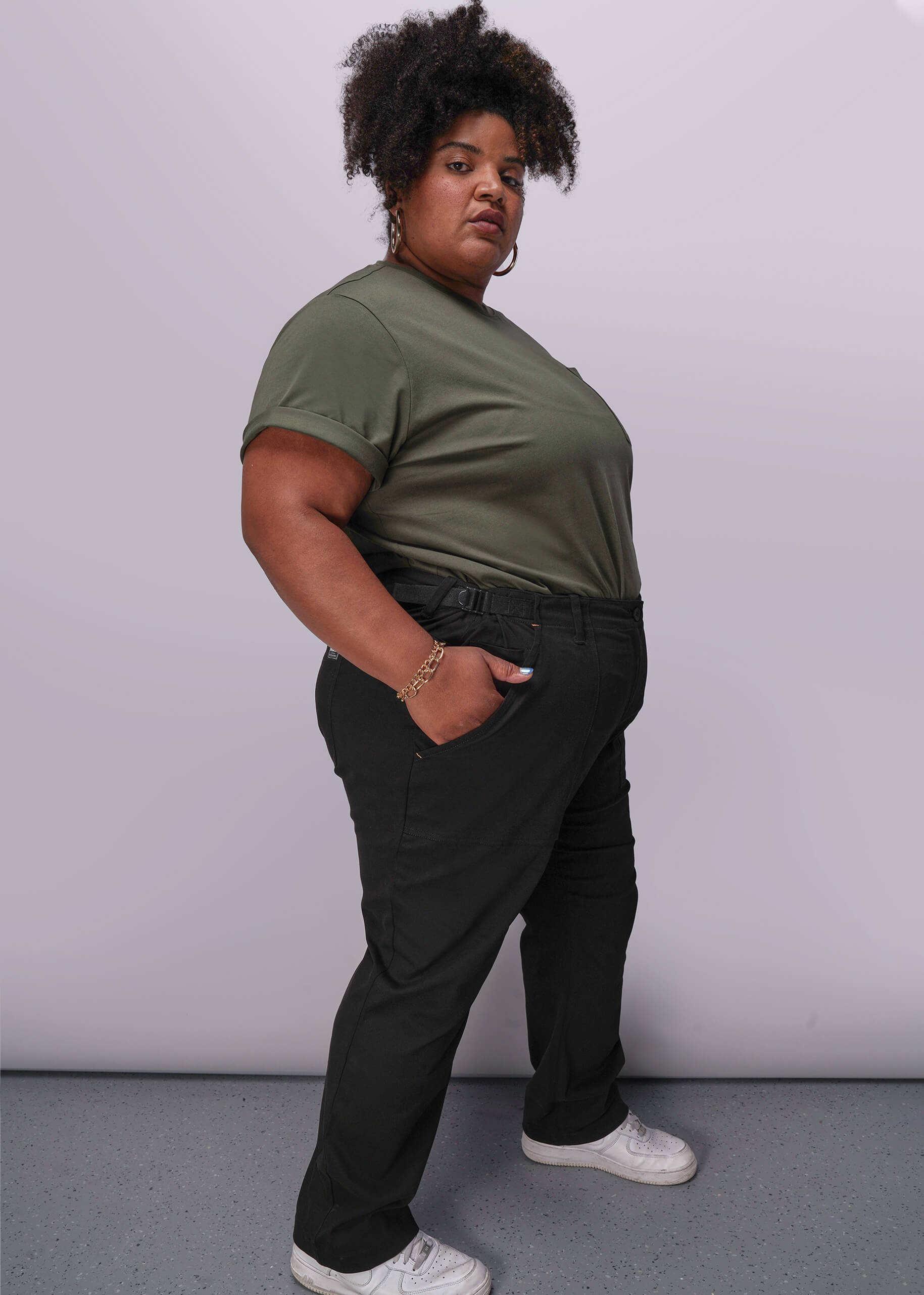 1X=Person wearing a green t-shirt and black pants against a plain background