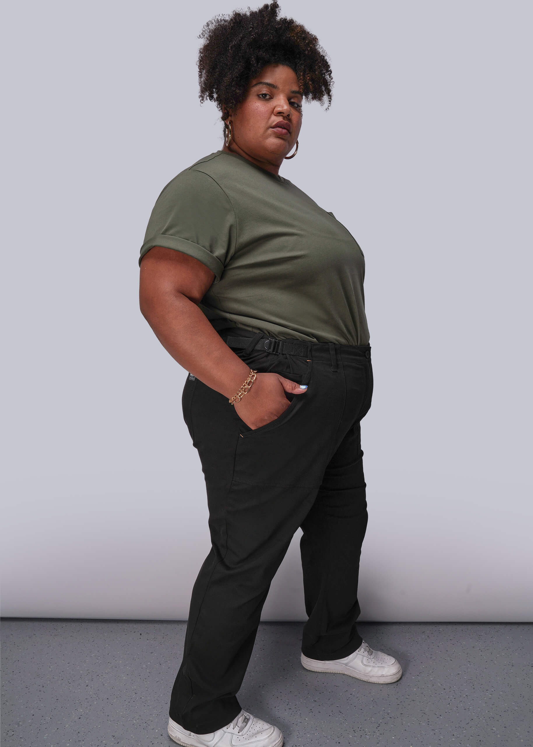 1X=Person wearing a green t-shirt and black pants against a plain background