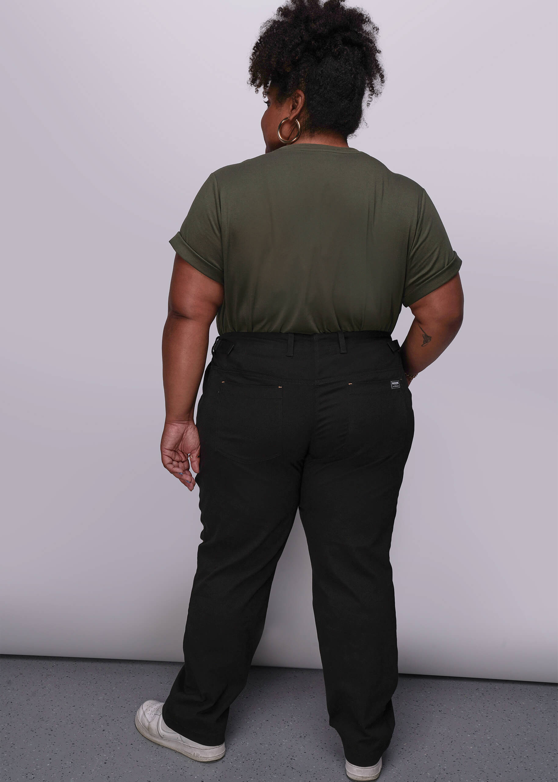 1X=Person wearing a green t-shirt and black pants against a white background