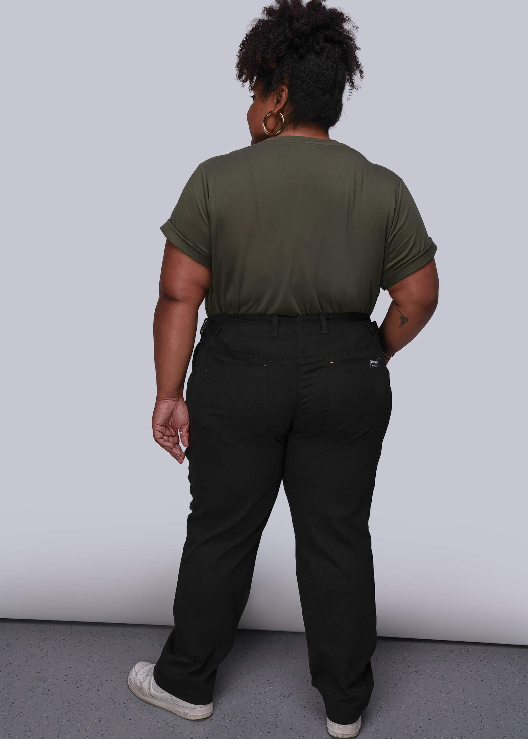 1X=Person wearing a green t-shirt and black pants against a white background