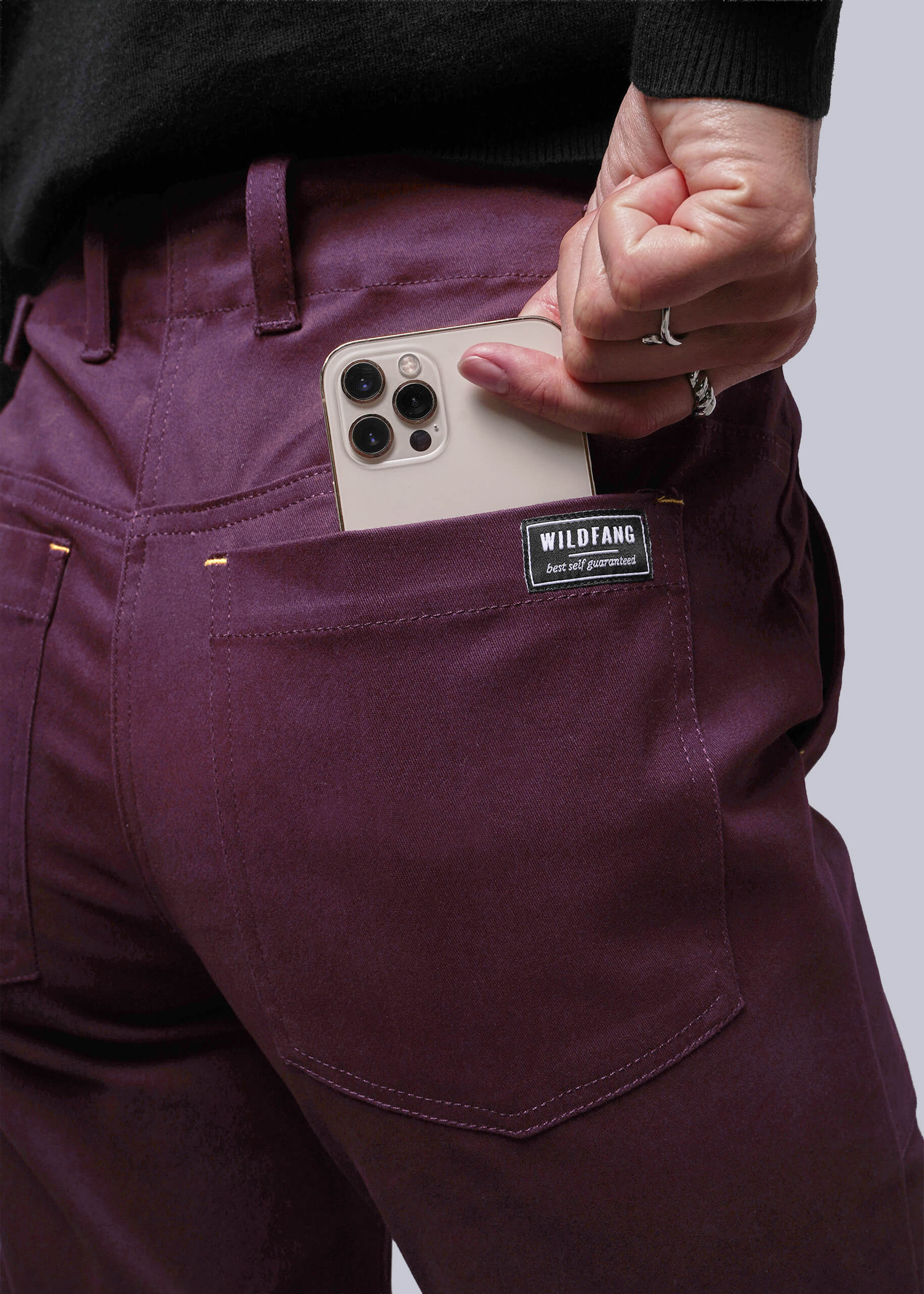 S=Person wearing burgundy pants with a phone in the pocket, featuring a visible brand label.