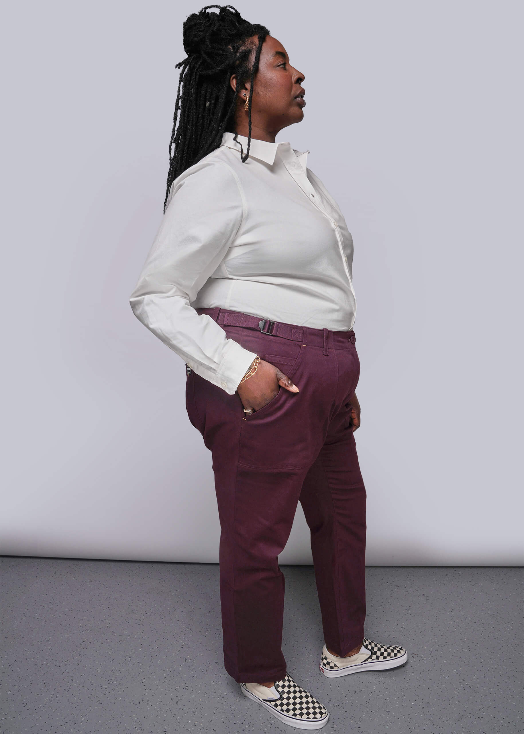 1X=Person wearing a white shirt and maroon pants against a plain background